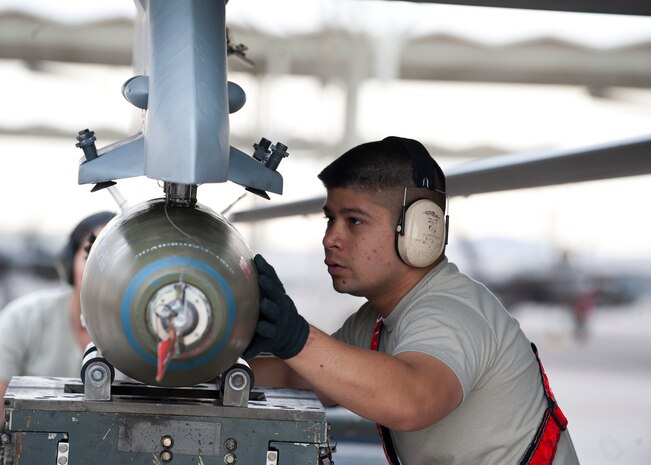 Staff Sgt. David Uncangco, 57th Aircraft Maintenance Squadron, Viper Aircraft Maintenance Unit load crew team chief, loads an inert munition onto an F-16 Fighting Falcon during the quarterly load crew competition on the flightline, April 11, 2014, at Nellis Air Force Base, Nev. Six load crews competed against one another to determine which crew can correctly load weapons onto their respective aircraft with zero write-ups. (U.S. Air Force photo by Airman 1st Class Thomas Spangler)