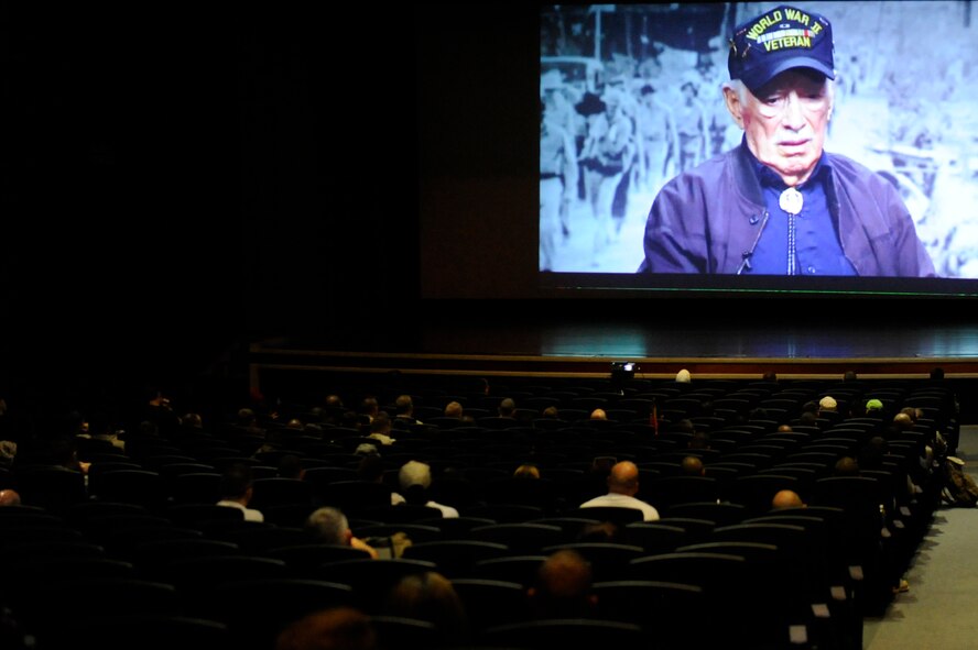 Joint military forces, civilian employees and their families watch a video of survivors recounting the events that transpired during the Bataan Death March on April 9, 1942, at the Keystone Theater on Kadena Air Base, Japan, April 12, 2014. Military members and civilians participated in an 8.5-mile march to commemorate the prisoners of war who were a part of the Battle of Bataan in the Philippines during World War II. (U.S. Air Force photo by Senior Airman Maeson L. Elleman)