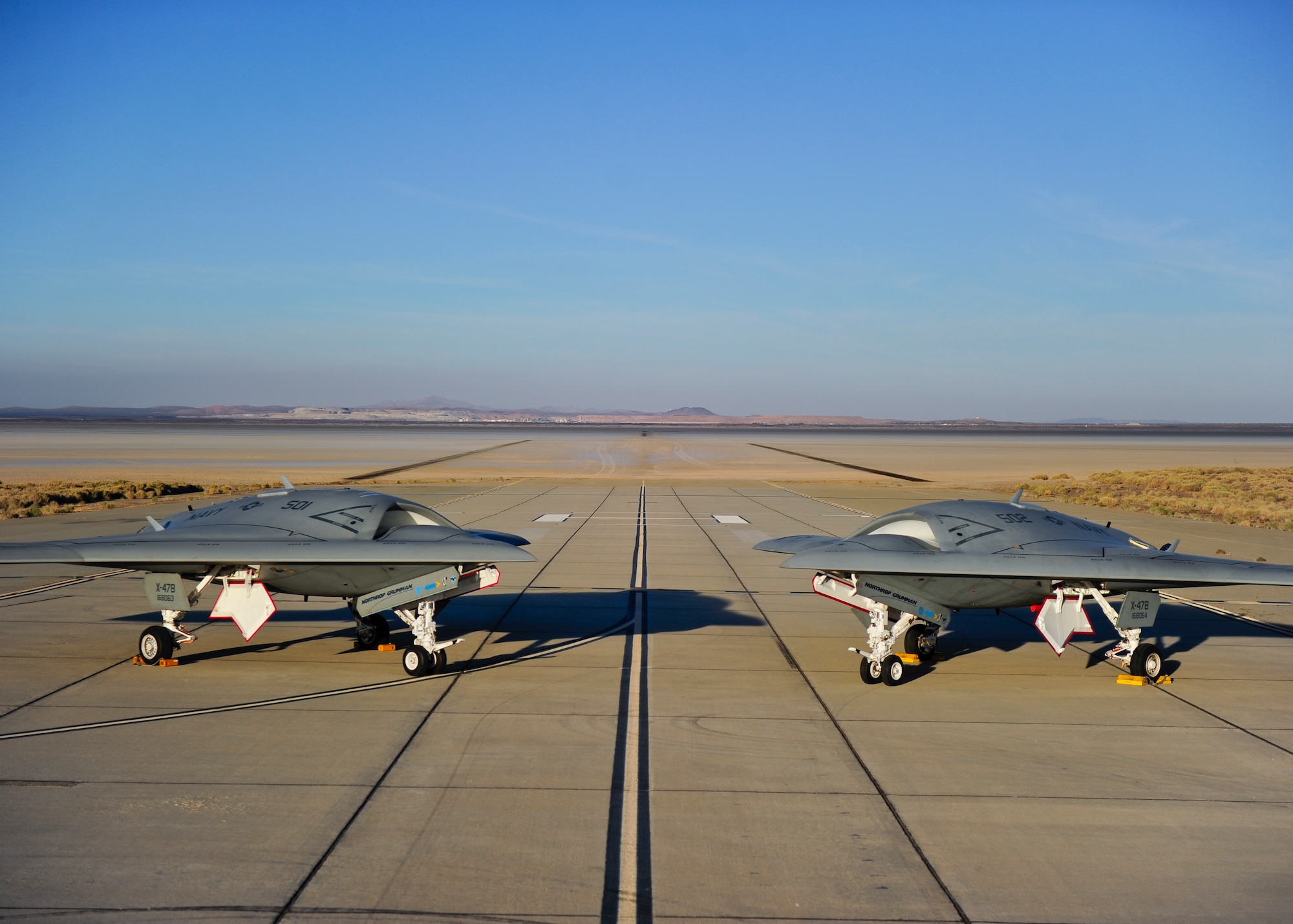 The two X-47B test aircraft pause between flight test events at Edwards AFB, Calif. The two vehicles were built by Northrop Grumman at Palmdale, California and performed all of their initial flight testing at Edwards AFB before transitioning to NAS Patuxent River in Maryland. (Northrop Grumman photo by Alan Radecki)