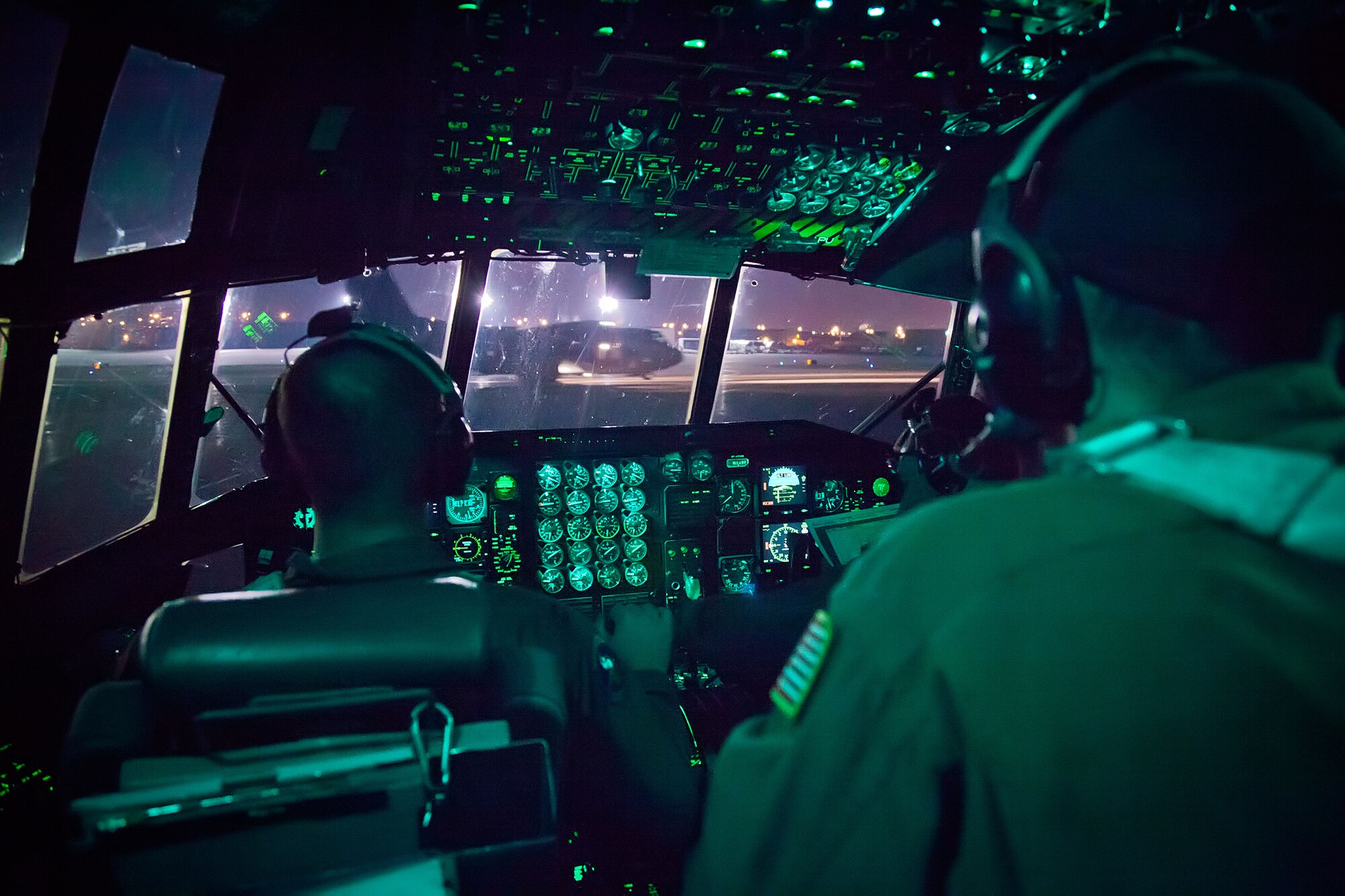 Capt. Andrew Reinhart and Staff Sgt. David Stein, 96th Airlift Squadron, wait and watch as another C-130 aircraft from in their four ship formation taxis to the runway at the Sioux Falls Airport, S.D., Saturday night. The weekend training missions for the 96th Airlift Squadron and 27th Aerial Port Squadron included preparing and deploying air drops, unscheduled landings, operating in night vision environment and deploying flares.  (U.S. Air Force photo by Shannon McKay/Released)