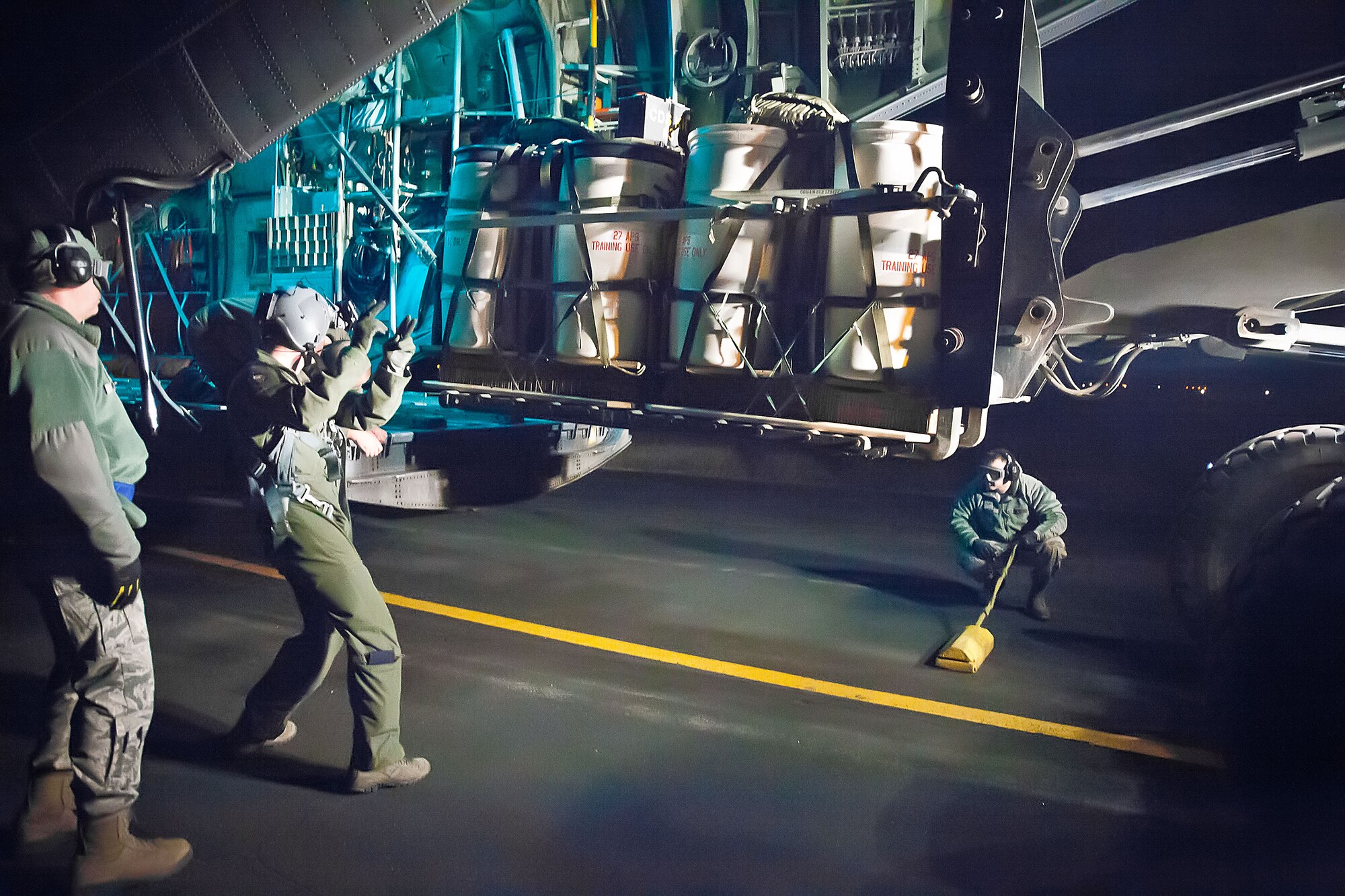 Chief Master Sgt. Dale Place, 27th Aerial Port Squadron, Senior Airmen Jesse Sunde, 96th Airlift Squadron, and Andrew Dudley, 27 APS, guide the pallet as it is loaded into a C-130 aircraft during a night flying exercise at Fort McCoy, Wis.  The weekend training mission included preparing and deploying air drops, unscheduled landings, operating in night vision environment and deploying flares.  (U.S. Air Force photo by Shannon McKay/Released)