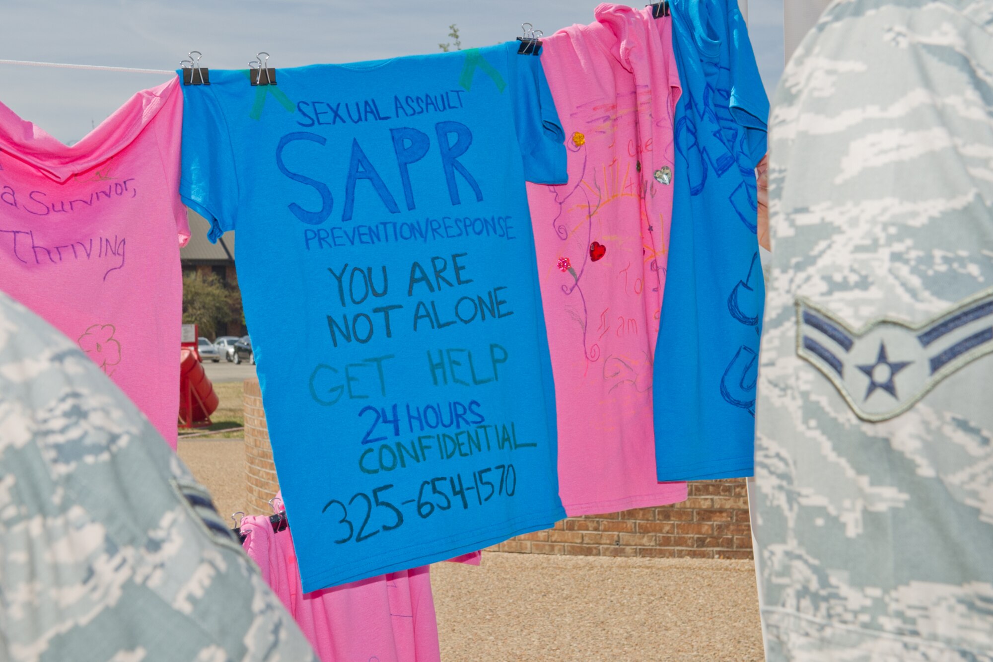 GOODFELLOW AIR FORCE BASE, Texas -- Base Airmen look at the Clothesline Project, t-shirts decorated by survivors of sexual assault or their family members to tell their stories, during Sexual Assault Awareness Month here April 11. The pink shirts represent women or female family members and the blue represent men or male family members who survived a sexual assault. (U.S. Air Force photo/ Staff Sgt. Laura R. McFarlane)