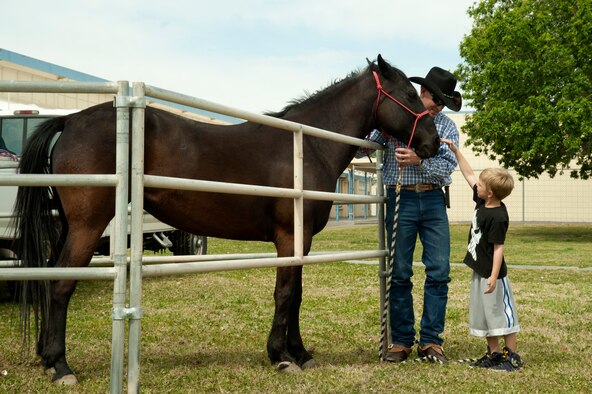 Tech. Sgt. Mike Hodges, 99th Medical Operations Squadron respiratory therapy technician, holds a horse while Anders Steinhiser, Lomie G. Heard Elementary School 1st grade student, reaches to pet it April 11, 2014, at Nellis Air Force Base, Nev. The horses were brought out to support the school’s career day event. (U.S. Air Force photo by Airman 1st Class Timothy Young)