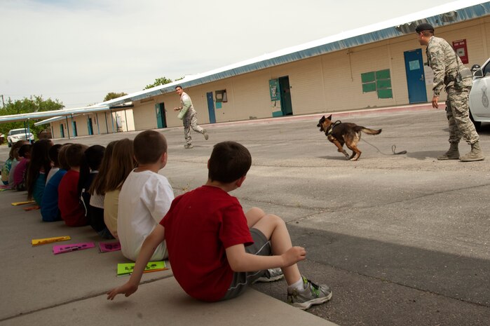 Second grade students at Lomie G. Heard Elementary School watch a military working dog handler demonstration April 11, 2014, at Nellis Air Force Base, Nev. The 99th Security Forces Squadron military working dog handlers provided the demonstration in support of the school’s career day event. (U.S. Air Force photo by Airman 1st Class Timothy Young)
