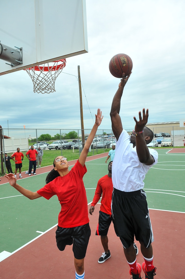 Michael Johnson ll elevates above the defense of Anissa Sidney during the basketball competition at the inaugural Air Force Intelligence, Surveillance and Reconnaissance Agency Field Day and Family Picnic at Security Hill's Stapleton Park April 5. The event is the unit's way of saying thanks to all who have sacrificed on its behalf. (U. S. Air Force photo by William Belcher)