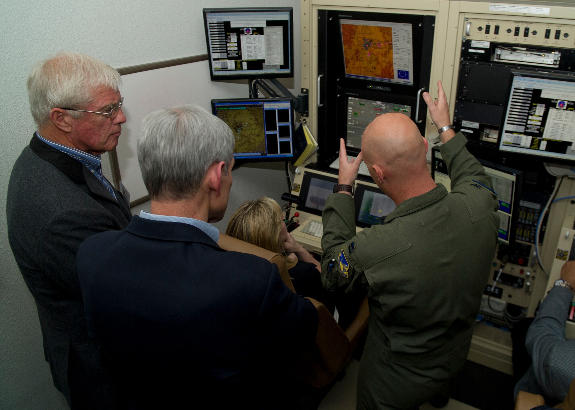 Captain Greg, 6th Reconnaissance Squadron MQ-1 Predator instructor pilot, demonstrates the usage of an MQ-1 Predator Remotely Piloted Aircraft simulator to retired General Norton Schwartz and staff members at Holloman Air Force Base, N.M., April 11. The Business Executives for National Security organization visits one military installation per month to exchange ideas on common issues and to further public and private partnerships. The visit featured 49th Wing and Team Holloman missions. (Last name withheld due to operations security.) (U.S. Air Force photo by Airman 1st Class Aaron Montoya / Released)