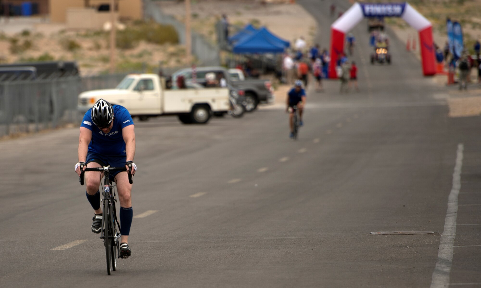 Cyclists pass through the finish line during the 18-mile men’s bicycle open April 9, 2014, at Nellis Air Force Base, Nev. The cyclists circled a 2-mile loop based upon how many miles they needed to accomplish for their particular race. (U.S. Air Force photo/Senior Airman Jette Carr)