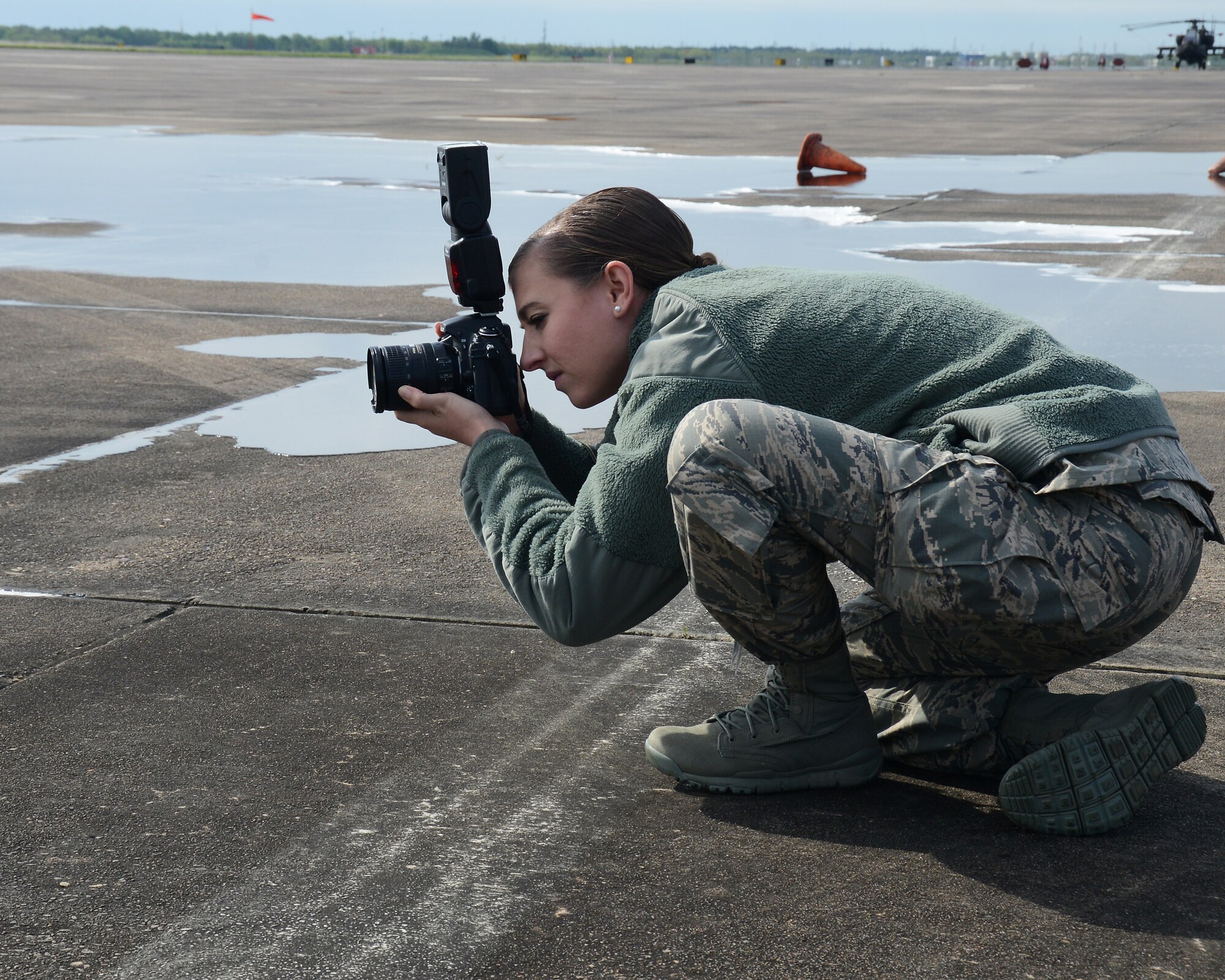 Senior Airman Chasity Lollis, 147th Reconnaissance Wing Public Affairs, squats down to shoot from a low perspective while photographing fire fighters extinguishing a simulated aircraft fire at Ellington Field Joint Reserve Base, April 5, 2014. The 147th Reconnaissance Wing participated in an Operational Readiness Exercise to test the wing's wartime readiness.