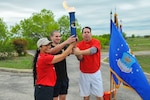 Left to right, Chief Master Sgt. Arleen Heath, Senior Airman Thomas Westrick and Maj. Gen. John Shanahan hoist the torch to open the inaugural Air Force Intelligence, Surveillance and Reconnaissance Agency Field Day and Family Picnic at Security Hill's Stapleton Park April 5. The event is the unit's way of saying thanks to all who have sacrificed on its behalf. (U. S. Air Force photo by William Belcher)