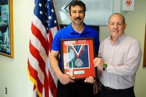 Mark Sciacchitano, 733rd Civil Engineer Division director, and Arba Williamson, 733rd CED pollution prevention specialist, pose for a photograph with the Silver Governor’s Environmental Excellence Award for Conservation at Fort Eustis, Va., April 10, 2014. The 733rd CED won the award for their efforts in protecting Fort Eustis’ cultural and natural assets. (U.S. Air Force photo by Senior Airman Austin Harvill/Released) (photo cropped, sharpened, color corrected and contrasted for effect)