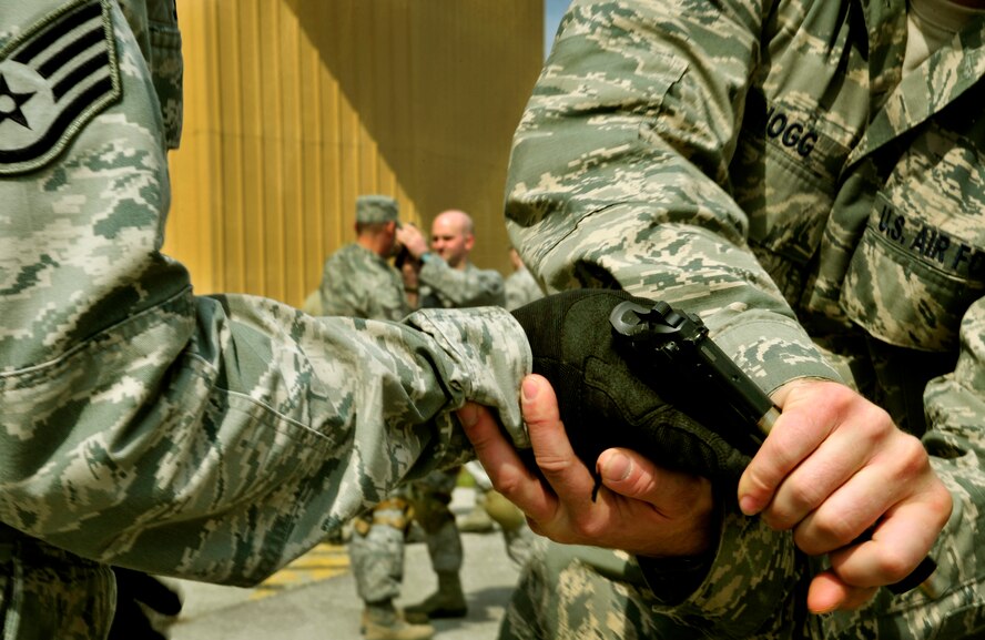 (Left to Right) Staff Sgt. Jonathan Hogg and Cody Shearer, Security Forces Squadron trainers practice defense tactics during Progressive Combat Solutions training at Scott Air Force Base, Ill., April 8, 2014. This training scenario will prepare members on how to defend themselves when a single person tries to take their weapon. The Progressive Combat Solutions trains military and law enforcement personnel in decision making process originally benchmarked by the Air Force known as observe, orient, decide and act. The Air Mobility Command and the 375th Security Force Squadron hosted this training with the goal of implementing it across the AMC command in the future. (U.S. Air Force photo/Staff Sgt. Stephenie Wade)