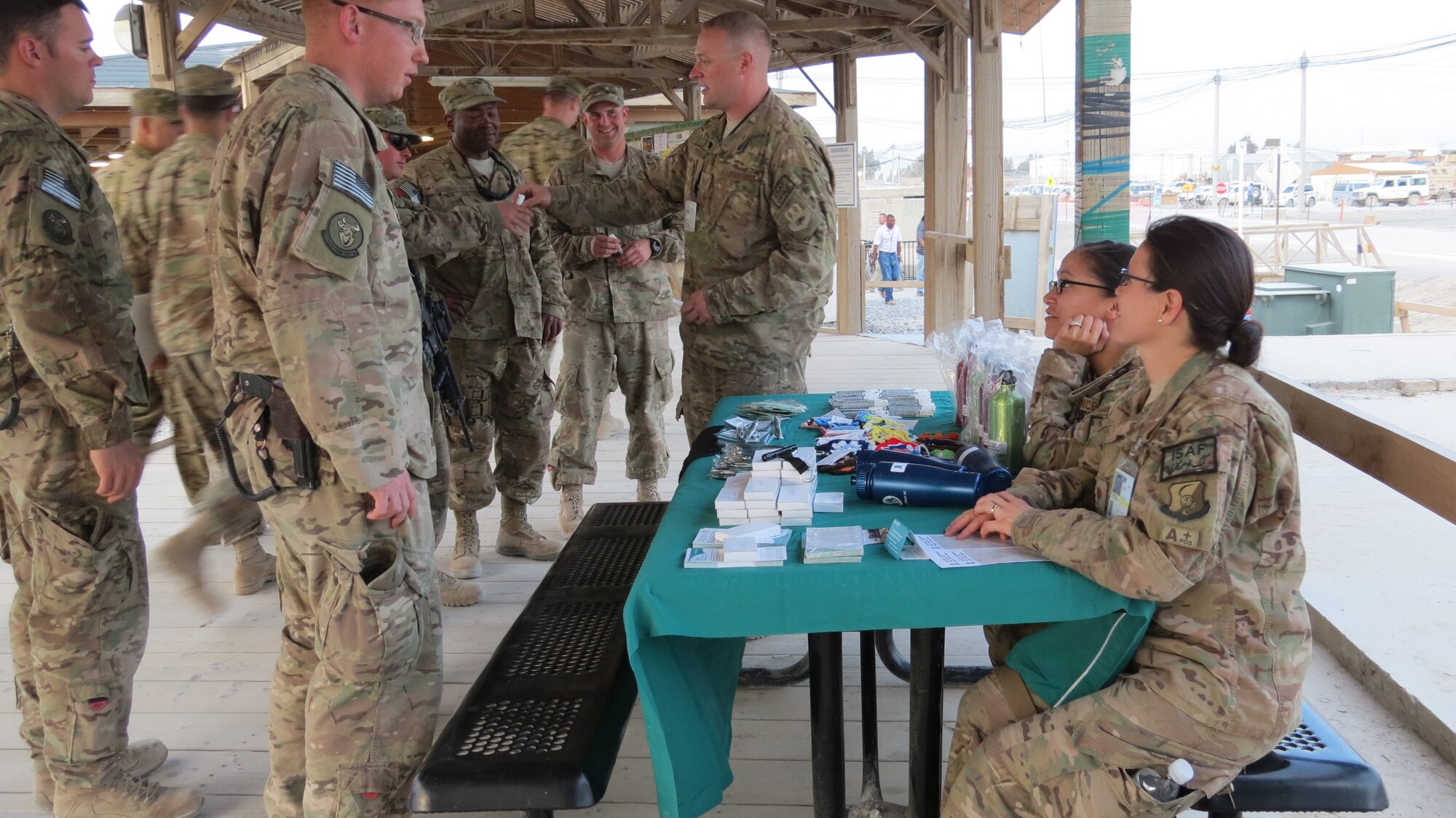 Technical Sergeant Simon Henry, 451st Expeditionary Logistics Readiness Squadron, hands out items promoting sexual assault awareness at Kandahar Airfield, Afghanistan April 12, 2014. Victim Advocates and volunteers set up a table at the boardwalk area to promote awareness during Sexual Assault Awareness Month. (U.S. Air Force Photo by Senior Airman Alexandria Bandin/Released)