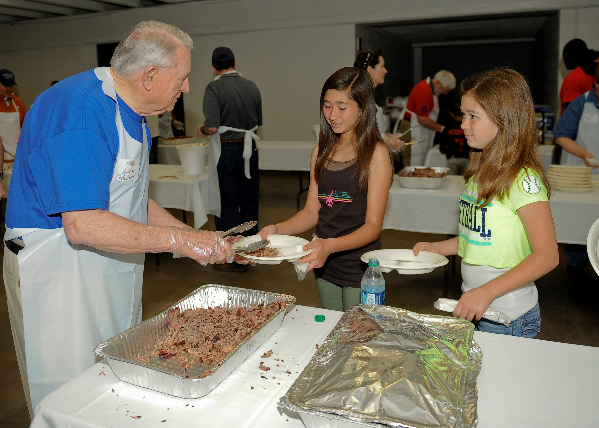 Lou Paulsen, a volunteer at the 49th Annual World’s Largest Barbecue, serves Alexa and Abigail beef brisket April 12, 2014 at the Civic Center in Abilene, Texas. Alexa and Abigail are the daughters of Lt. Col. Scott Higginbotham, 7th Operations Group. The barbecue was made possible with the help of more than 190 volunteers and a dozen barbecue handlers, also known as the “Dirty Dozen”. The Abilene Chamber of Commerce Military Affairs Committee had more than 3,300 pounds of beef donated to feed more than 5,000 active duty military, retirees and their families. (U.S. Air Force photo by Airman 1st Class Kedesha Pennant/Released)



