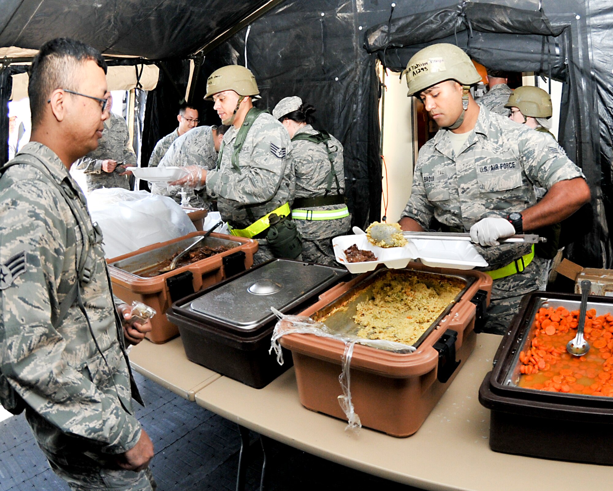 Senior Airman Fahim Baqui from the 147th Reconnaissance Wing Force Support Squadron at Ellington Field FRB, Houston serves a unitized group ration meal in a single pallet expeditionary kitchen during an Operational Readiness Exercise, April 4, 2014. The exercise tested the Wing's ability to respond to various wartime scenarios in an effort to promote unit readiness and efficiency.