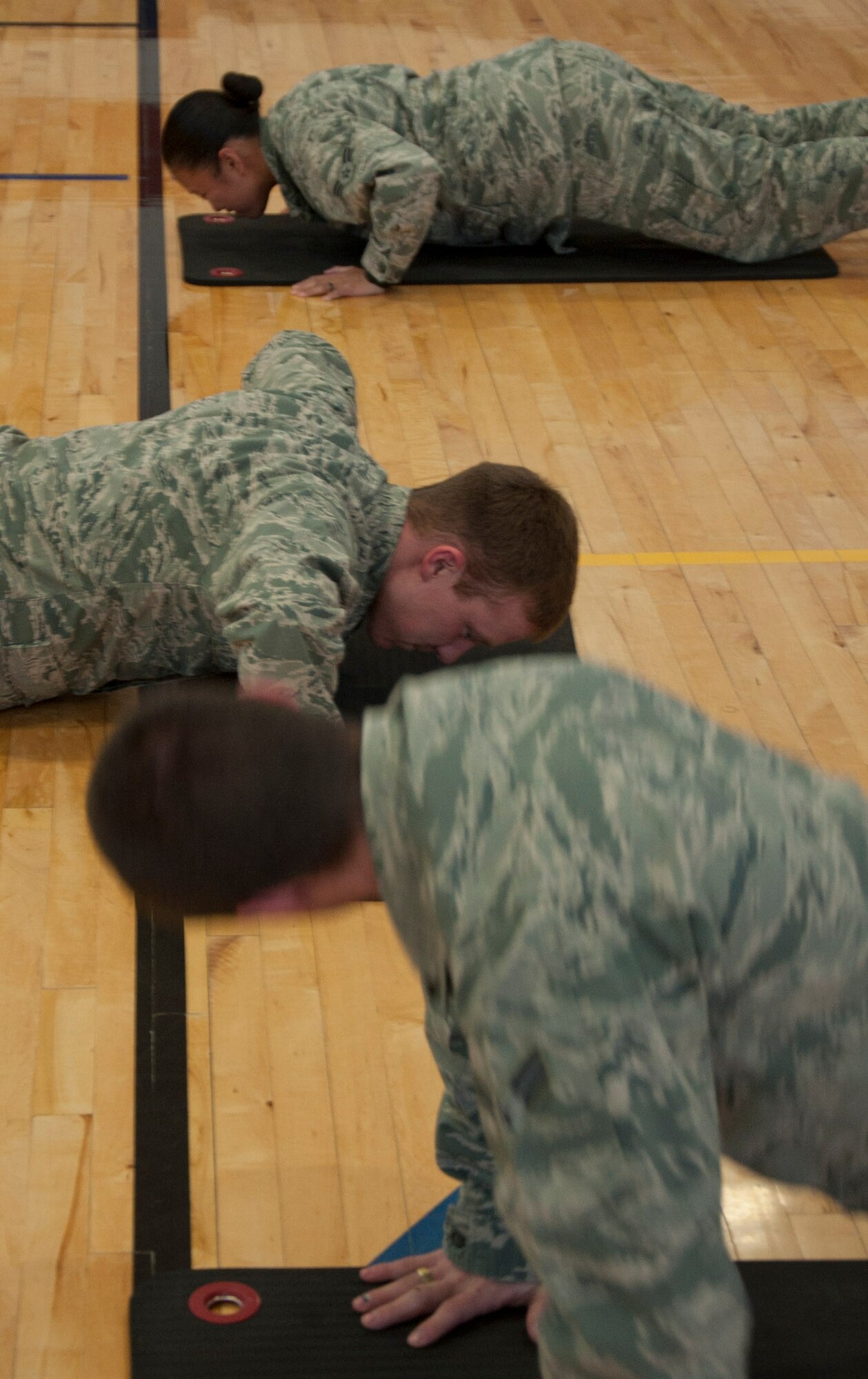 140415-F-GZ967-019 Airman 1st Class Jonaelisha Medina, Airman Joshua Szajko, and Airman 1st Class Louis Epperson, 90th Comptroller Squadron, do push-ups April 15 during the Sexual Assault Awareness Month confidence course in the Freedom Hall Fitness Center. Since most of the obstacles were simple and fun, participants were asked a series of questions at the end each obstacle to increase the awareness of sexual assaults. (U.S. Air Force photo by Airman 1st Class Brandon Valle)