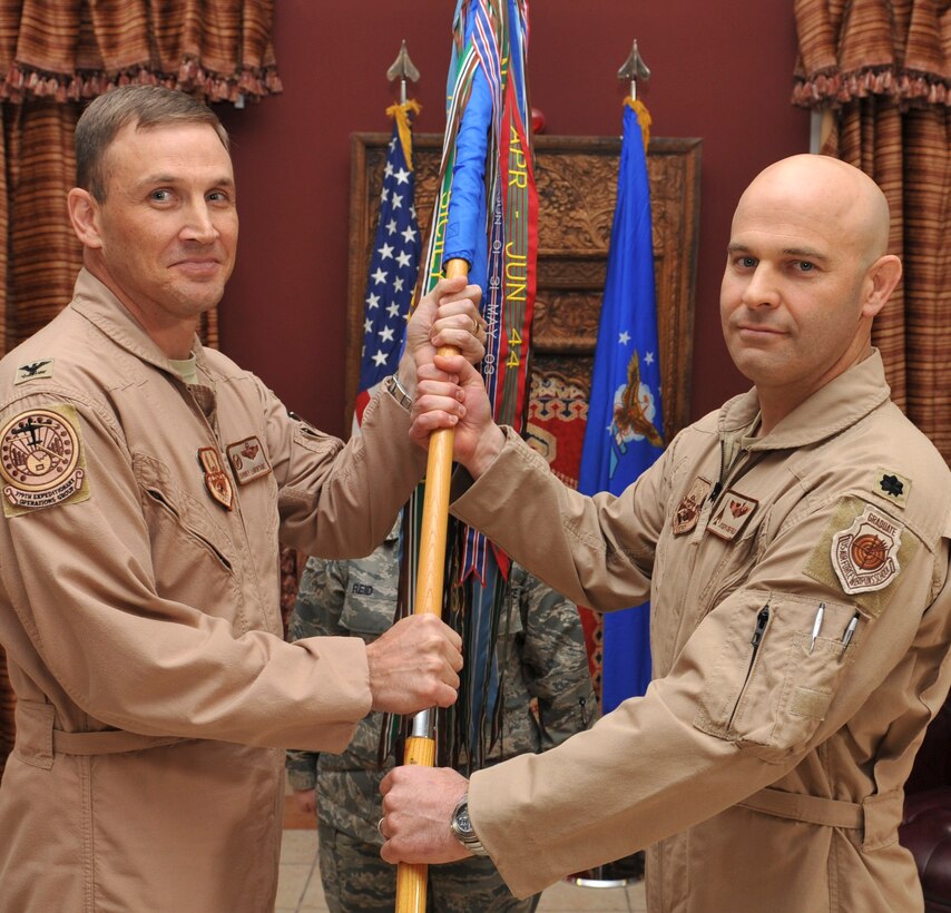 Col. John LaMontagne, 379th Expeditionary Operations Group commander, passes the 37th Expeditionary Bomb Squadron guidon to Lt. Col. Joseph Sheffield as he assumes command of the 37th EBS during a change of command ceremony at a forward operating location in Southwest Asia, April 4, 2014. More than 350 Airmen and a portion of Ellsworth's B-1 fleet continue to provide multi-role airpower in support of U.S. and coalition forces in that region of the world. (U.S. Air Force Photo by Master Sgt. David Miller/Released)