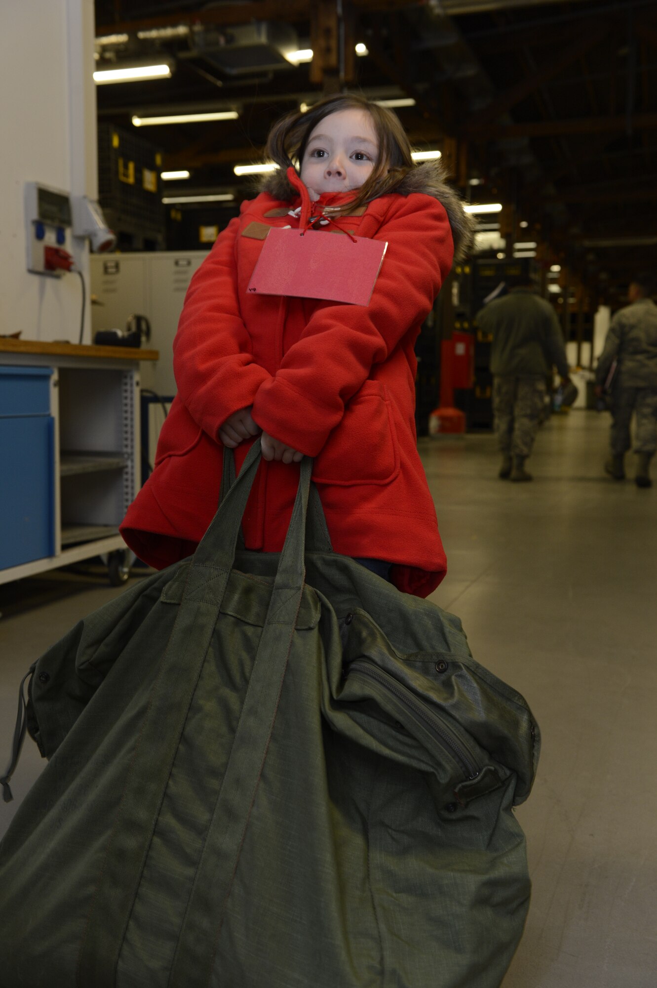 Elizabeth Faraone, daughter of U.S. Air Force Capt. Joseph Faraone, 606th Air Control Squadron, attempts to lift a fully packed mobility bag during Kids' Deployment Day at Spangdahlem Air Base, Germany, April 15, 2014. Spangdahlem Airmen invited students from the Bitburg and Spangdahlem Elementary Schools to experience what their parents go through during a deployment. (U.S. Air Force photo by Staff Sgt. Christopher Ruano/Released)