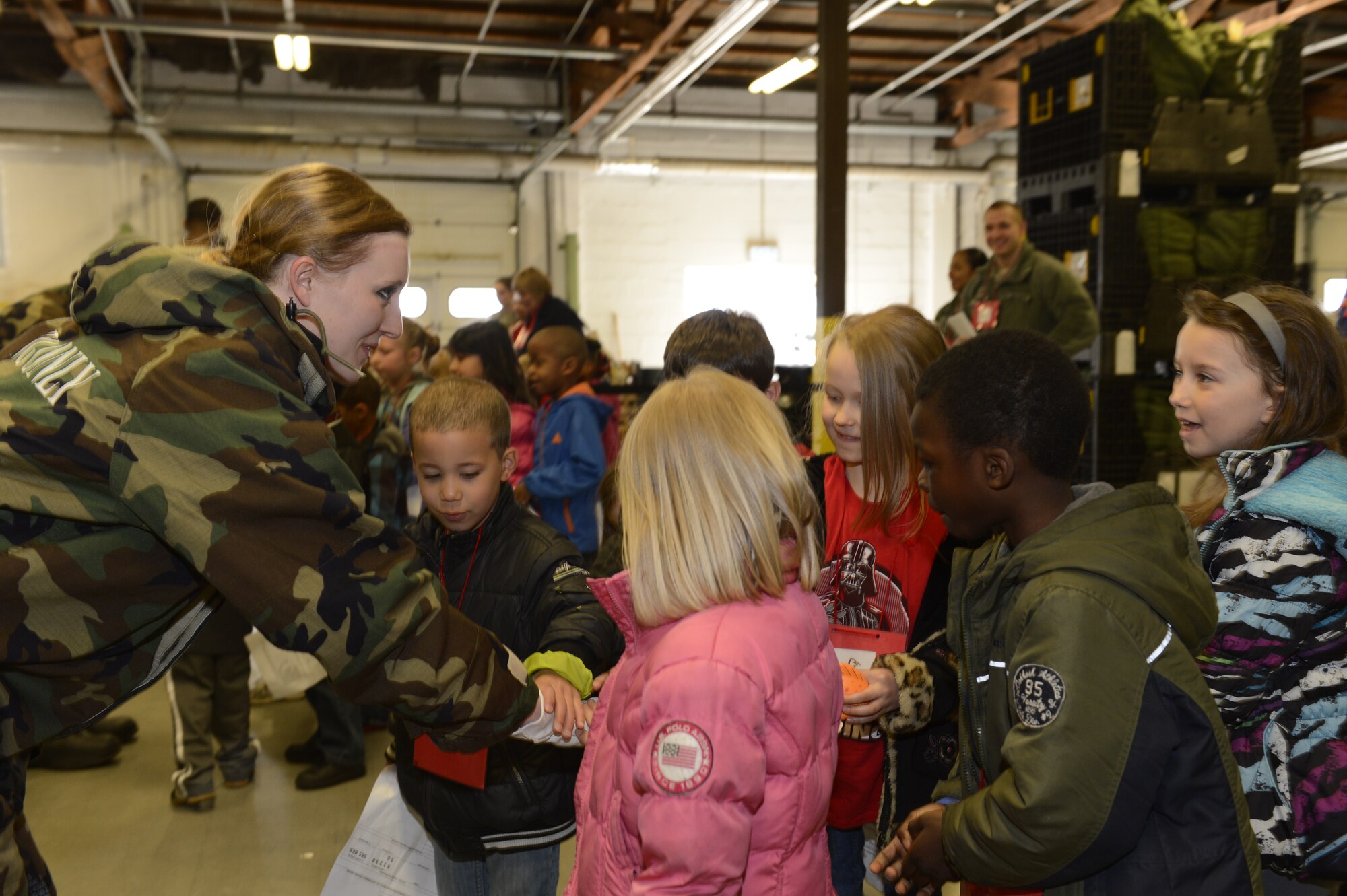Students from Bitburg and Spangdahlem Elementary Schools gain firsthand experience of the mission oriented protective posture gear worn by U.S. Air Force Senior Airman Sarah Dumas, 52nd Logistics Readiness Squadron, central storage technician from Bowling Green, Ohio, during Kids' Deployment Day April 15, 2014, at Spangdahlem Air Base, Germany. Airmen allowed students to feel and try on military protective gear during the event. (U.S. Air Force photo by Staff Sgt. Christopher Ruano/Released)
