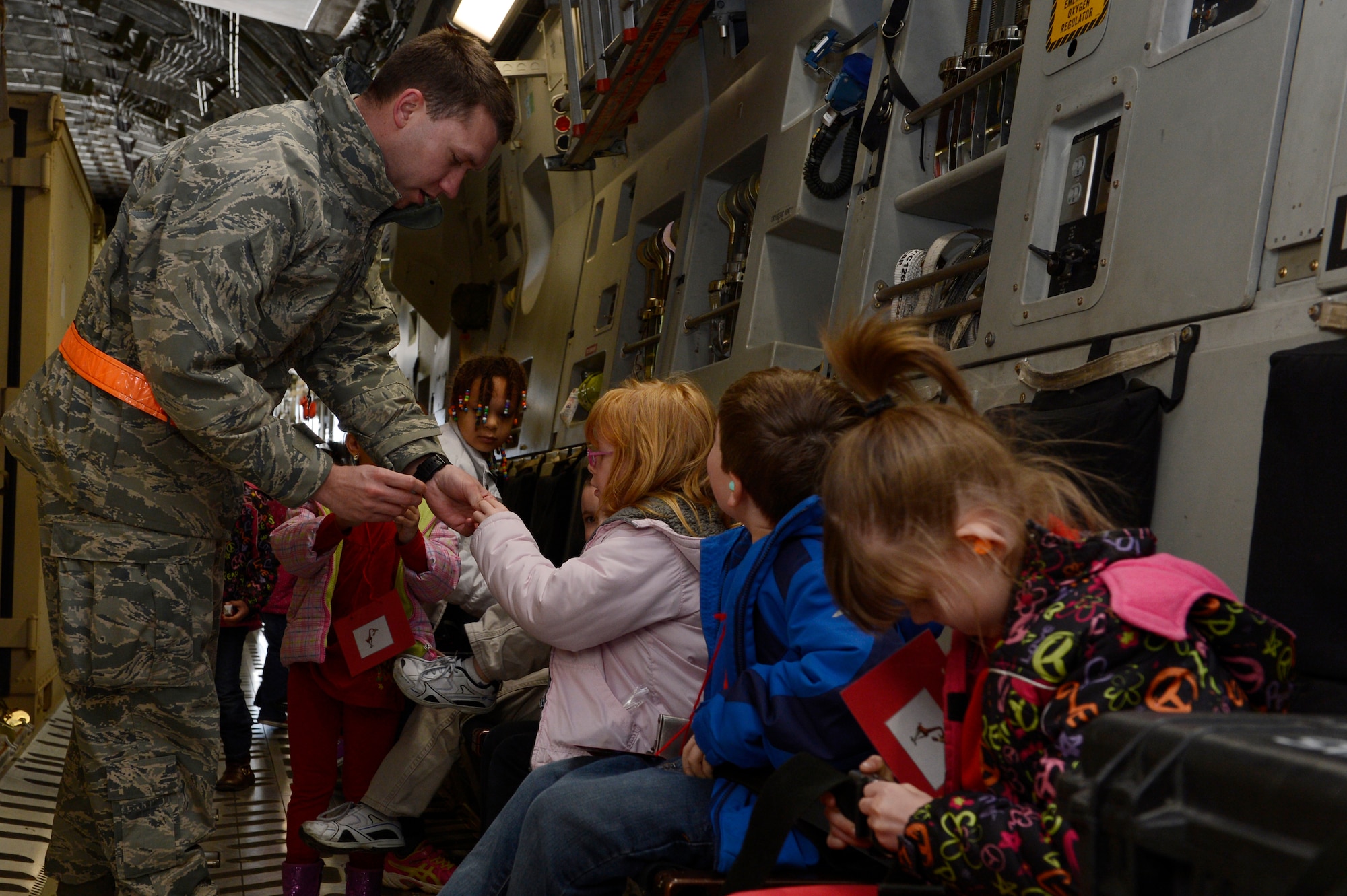 U.S. Air Force Senior Airman Nathan Stephenson, 726th Air Mobility Squadron controller from Bryson, Texas, buckles in children during Kids' Deployment Day April 15, 2014, at Spangdahlem Air Base, Germany. Base organizers held the event for students from the Bitburg and Spangdahlem Elementary Schools. (U.S. Air Force photo by Staff Sgt. Christopher Ruano/Released)