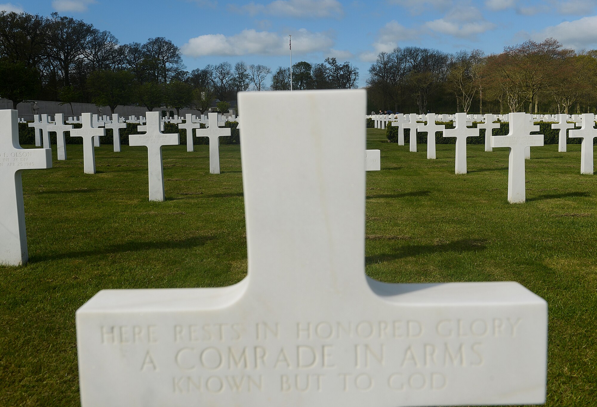 A headstone at the Madingley American Military Cemetery and Memorial in Cambridge, England, reads “Here rests in honored glory a comrade in arms known but to God” to represent an unidentified veteran April 13, 2014. Personnel from the 48th Munitions Squadron volunteered their time to clean the grounds and headstones of the cemetery. (U.S. Air Force photo by Airman 1st Class Trevor T. McBride/Released)