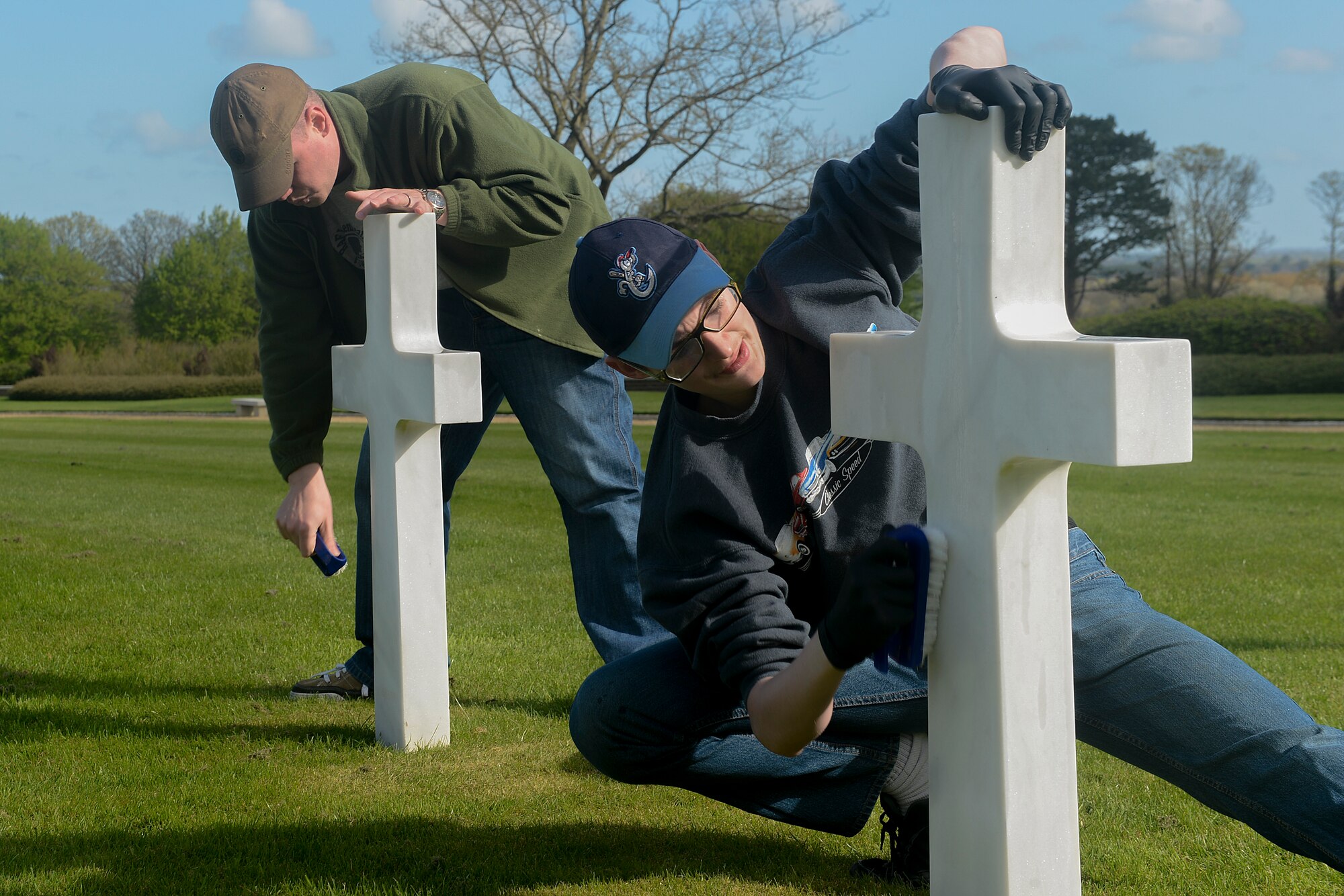 Master Sgt. Thurman McNece (left), 48th Munitions Squadron, assistant NCO in charge, and his son Gabriel, clean headstones at the Madingley American Cemetery and Memorial in Cambridge, England, April 13, 2014. The 48th MUNS personnel volunteered their time to clean the grounds and headstones of the cemetery. (U.S. Air Force photo by Airman 1st Class Trevor T. McBride/Released)