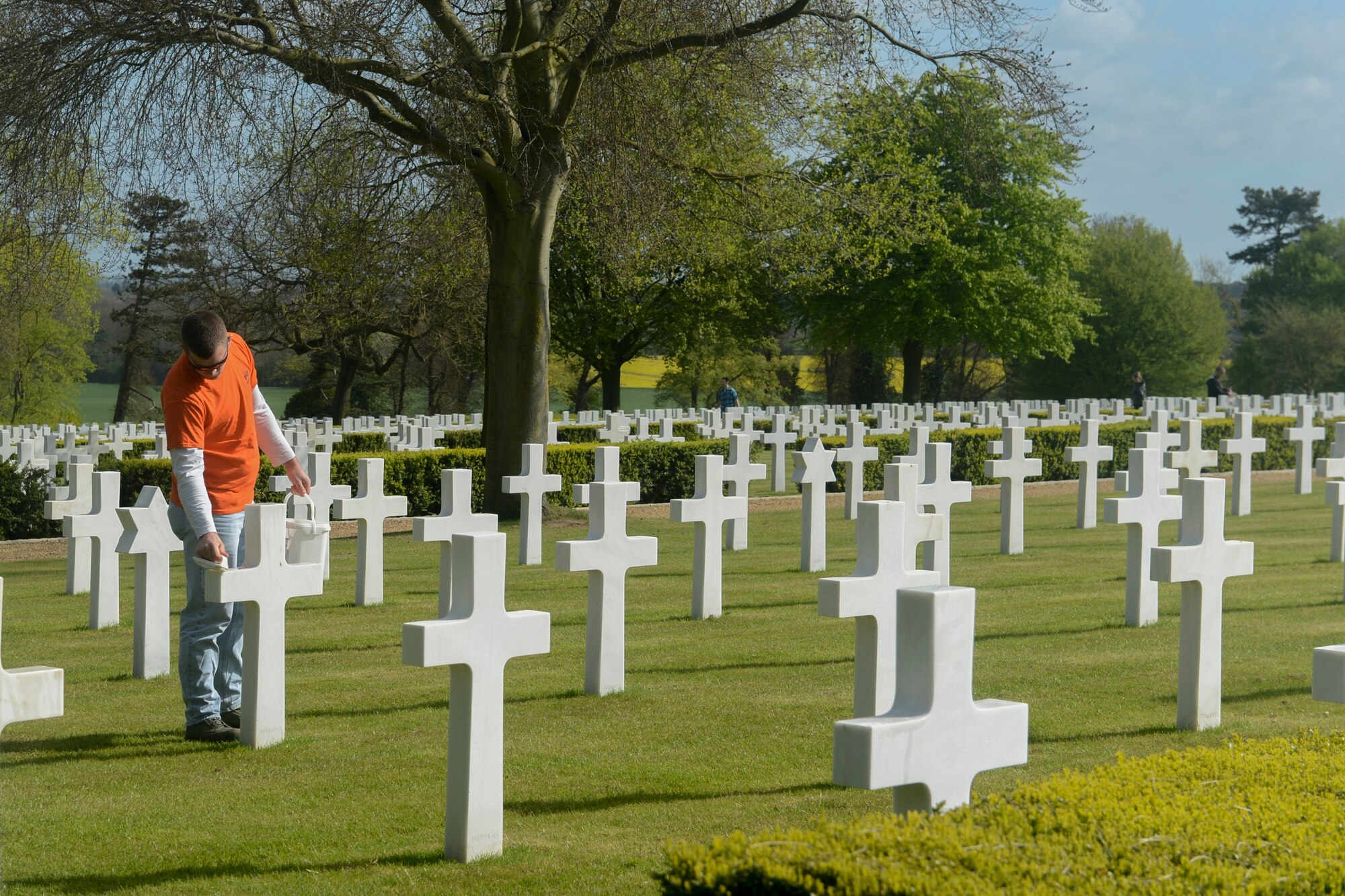 Senior Airman Adam Pawlak, 48th Munitions Squadron precision-guided munitions crew chief, cleans headstones at the Madingley American Cemetery and Memorial in Cambridge, England, April 13, 2014. The 48th MUNS personnel volunteered their time to clean the grounds and headstones of the cemetery. (U.S. Air Force photo by Airman 1st Class Trevor T. McBride/Released)