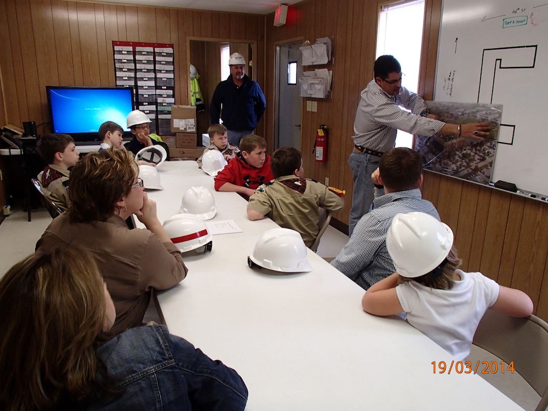 Bill Cottle, Balfour Beatty project manager, shows a troop of Webelos an aerial view artist rendition of the completed EAB Barracks Facility at Fort Campbell.  