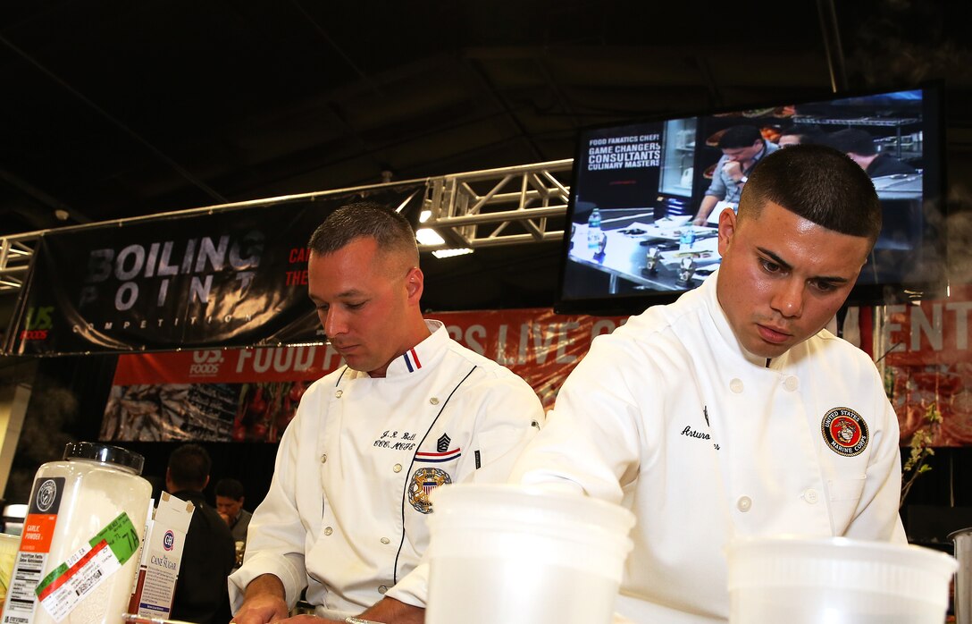 Gunnery Sgt. Justin Bell and Sgt. Arturo Torres cook during the Boiling Points competition held at the Del Mar Fairgrounds April 16. Boiling Points is a competition hosted by Aaron Williams, the corporate division chef for Food Fanatics, Los Angeles. The competition challenged the Marine Corps, Army, Navy and Coast Guard to go head-to-head in a 45-minute cooking competition. The Marine team took 1st place with their dish of an appetizer of fried eggplant and seared scallop caprese, and an entrée of seared duck, sweet potatoes and a fruit medley with a star fruit and horn melon sauce. Bell is the enlisted aide for the Marine Corps Recruit Depot’s commanding general and Torres is the chief cook for the 62 Area Mess hall on Camp Pendleton.
