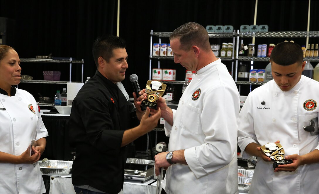 Aaron Williams presents Gunnery Sgt. Matthew Jacobs with the 1st place trophy during the Boiling Points competition held at the Del Mar Fairgrounds April 16. Boiling Points is a competition hosted by Aaron Williams, the corporate division chef for Food Fanatics, Los Angeles. The competition challenged the Marine Corps, Army, Navy and Coast Guard to go head-to-head in a 45-minute cooking competition. The Marine team took 1st place with their dish of an appetizer of fried eggplant and seared scallop caprese, and an entrée of seared duck, sweet potatoes and a fruit medley with a star fruit and horn melon sauce. Jacobs is the enlisted aid for the I Marine Expeditionary Force’s commanding general.