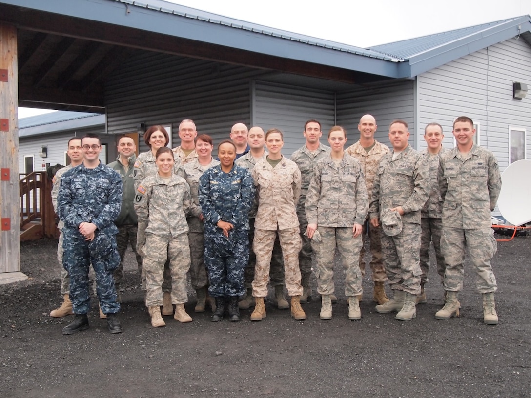 Service members stand together in the town of Old Harbor, Alaska during exercise Artic Care April 2, 2014. Exercise Arctic Care brought teams of personnel from all branches of the Armed Forces to Kodiak Island to administer needed care and medical education to the communities of Akhiok, Karluk, Larsen Bay, Port Lions, Ouzinke, Old Harbor, and the town of Kodiak. Such places where sea and air are the only methods of travel, dental and medical services can be hard to find.