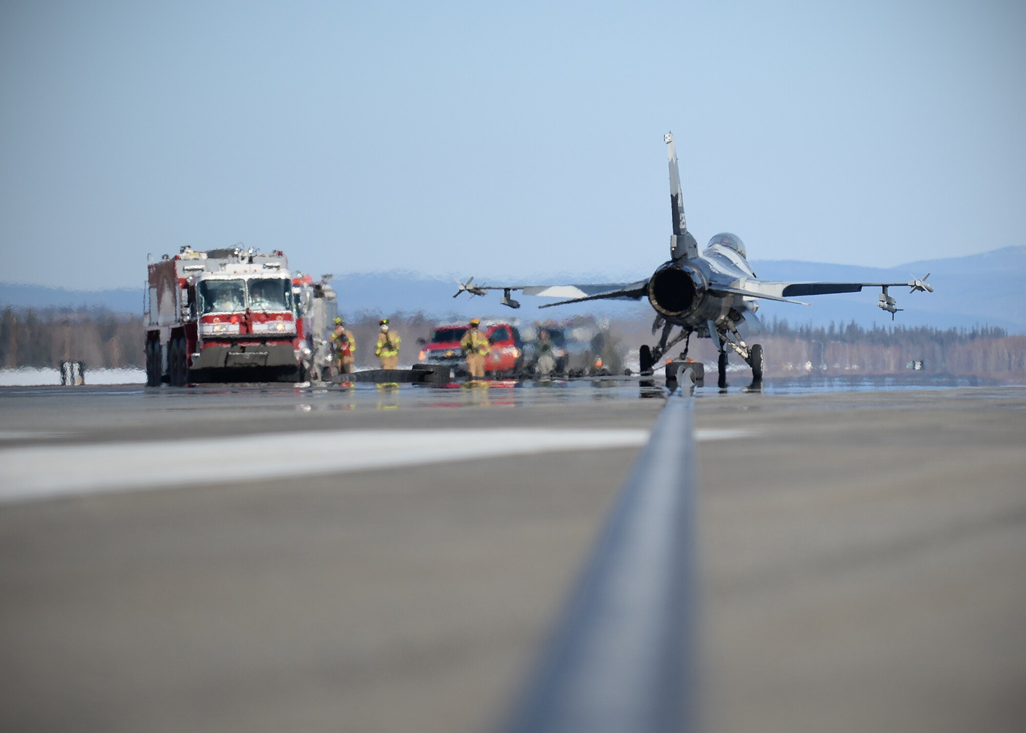 Members of the 354th Civil Engineer Squadron check an 18th Aggressor Squadron F-16 Fighting Falcon to ensure the engine did not catch fire April 11, 2014, Eielson Air Force Base, Alaska. Crash recovery team members from the 354th Maintenance Squadron worked with the fire department to deploy the arresting cable system for annual certification training. (U.S. Air Force photo by Staff Sgt. Shawn Nickel/Released)