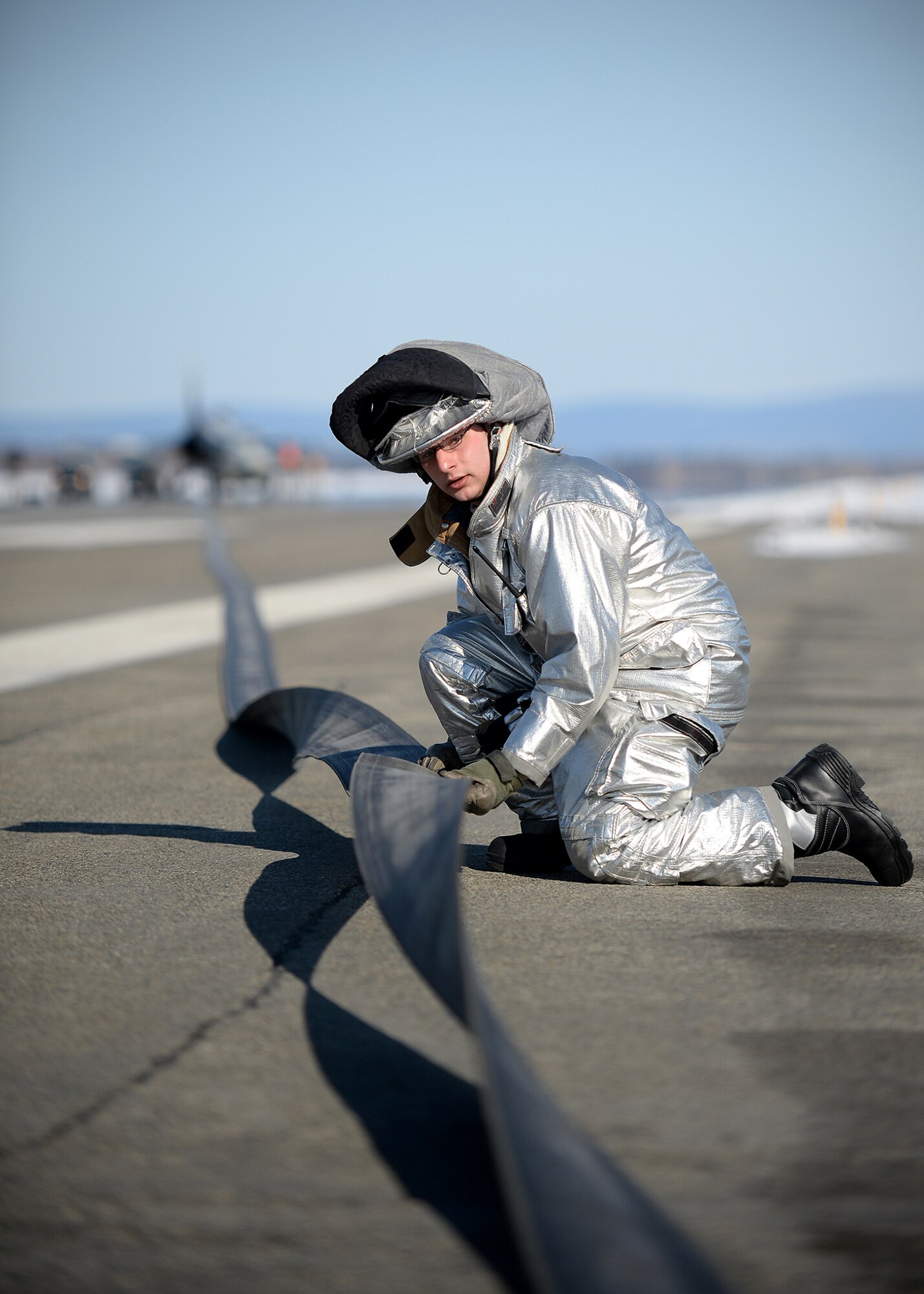 A firefighter from the 354th Civil Engineer Squadron inspects an arresting cable April 11, 2014, Eielson Air Force Base, Alaska. The arresting cable system is tested annually and is designed to slow down an aircraft in an emergency. (U.S. Air Force photo by Staff Sgt. Shawn Nickel/Released)