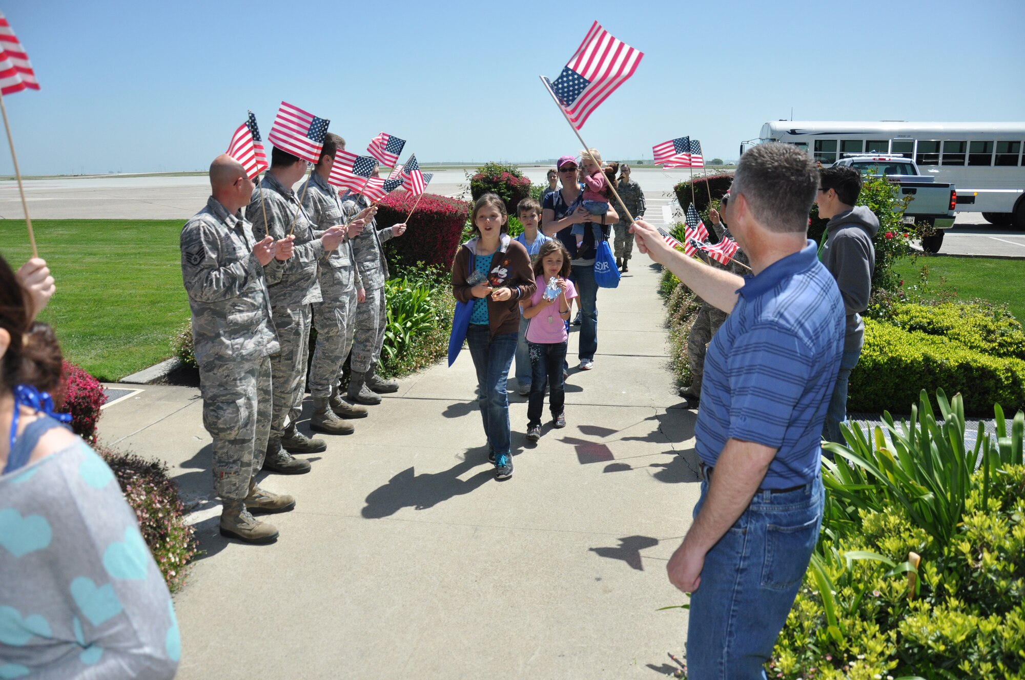 Children and family members are welcomed home upon completion of their mock deployment by Airmen and volunteers of Kids Understanding Deployment Operations April 12 at Travis. The event began at P-1 with an inprocessing line, mission brief, gear issue display, aircraft static displays, transport to a mock deployment to base X and ending at base operations. (U.S. Air Force photo/Staff Sgt. Christopher Carranza)