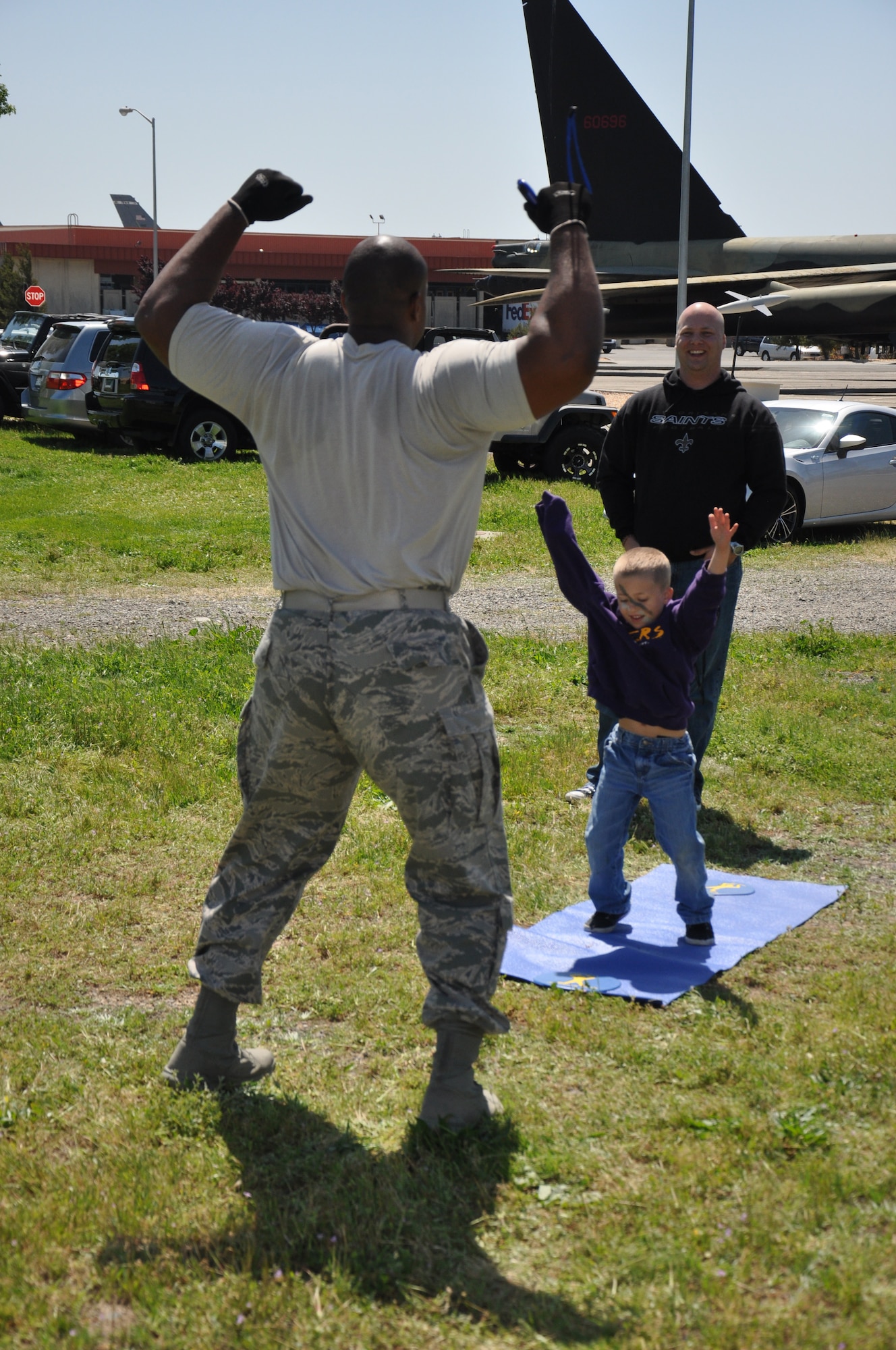 Tech. Sgt. Perry Navarro-Davis, 60th Security Forces Squadron unit training manager, demonstrates to a child the proper form to do jumping jacks during the phycial exercise station of Kids Understanding Deployment Operations April 12 at Travis. Throughout the event children were taught about the deployment process service members experience. (U.S. Air Force photo/ Staff Sgt. Christopher Carranza)