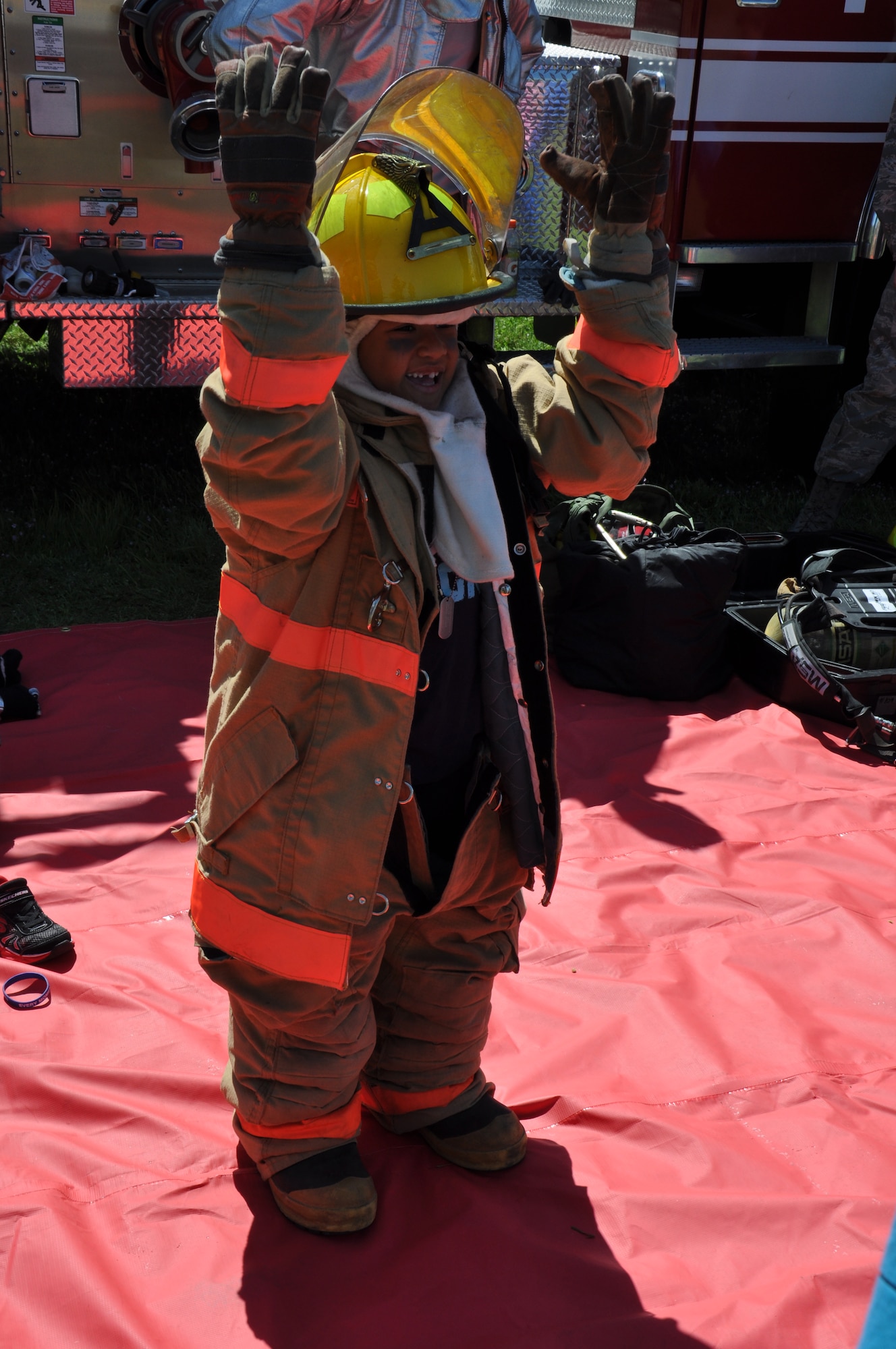A child dons the 60th Civil Engineer's firefighter equipment at the fire department display station during Kids Understanding Deployment Operations April 12 at Travis. The simulated deployment lasted approximately three hours with groups deploying every 15 minutes. (U.S. Air Force photo/ Staff Sgt. Christopher Carranza)