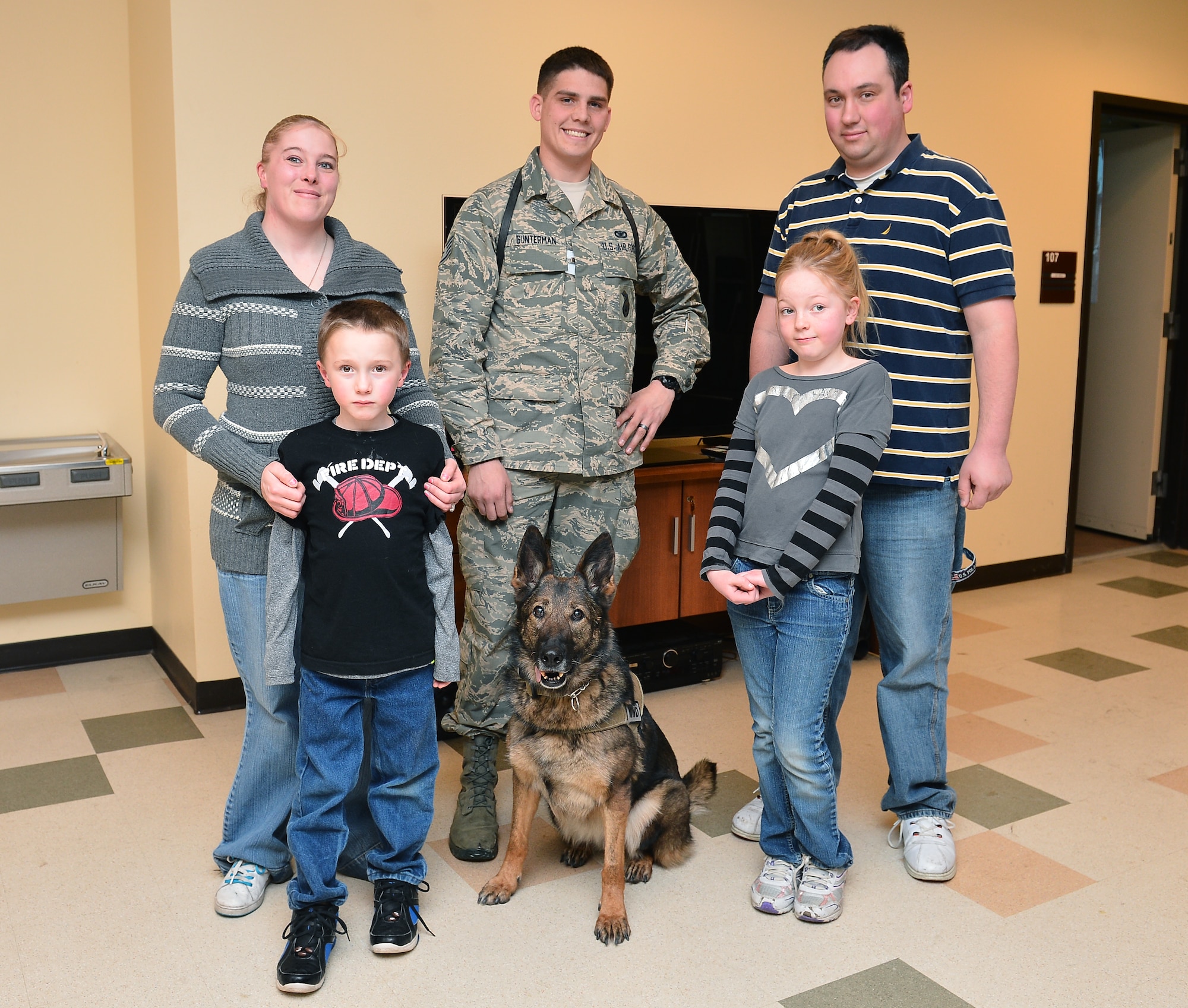 Staff Sgt. Jordan Gunterman, 460th Security Forces Squadron military working dog handler, center, and Nina, MWD, stand with the Wulfers family Jan. 23, 2014, in the 460th SFS kennels on Buckley Air Force Base, Colo. Gunterman was the first responder to a drunken driving car accident that affected the Wulfers family. (U.S. Air Force photo by Senior Airman Riley Johnson/Released)