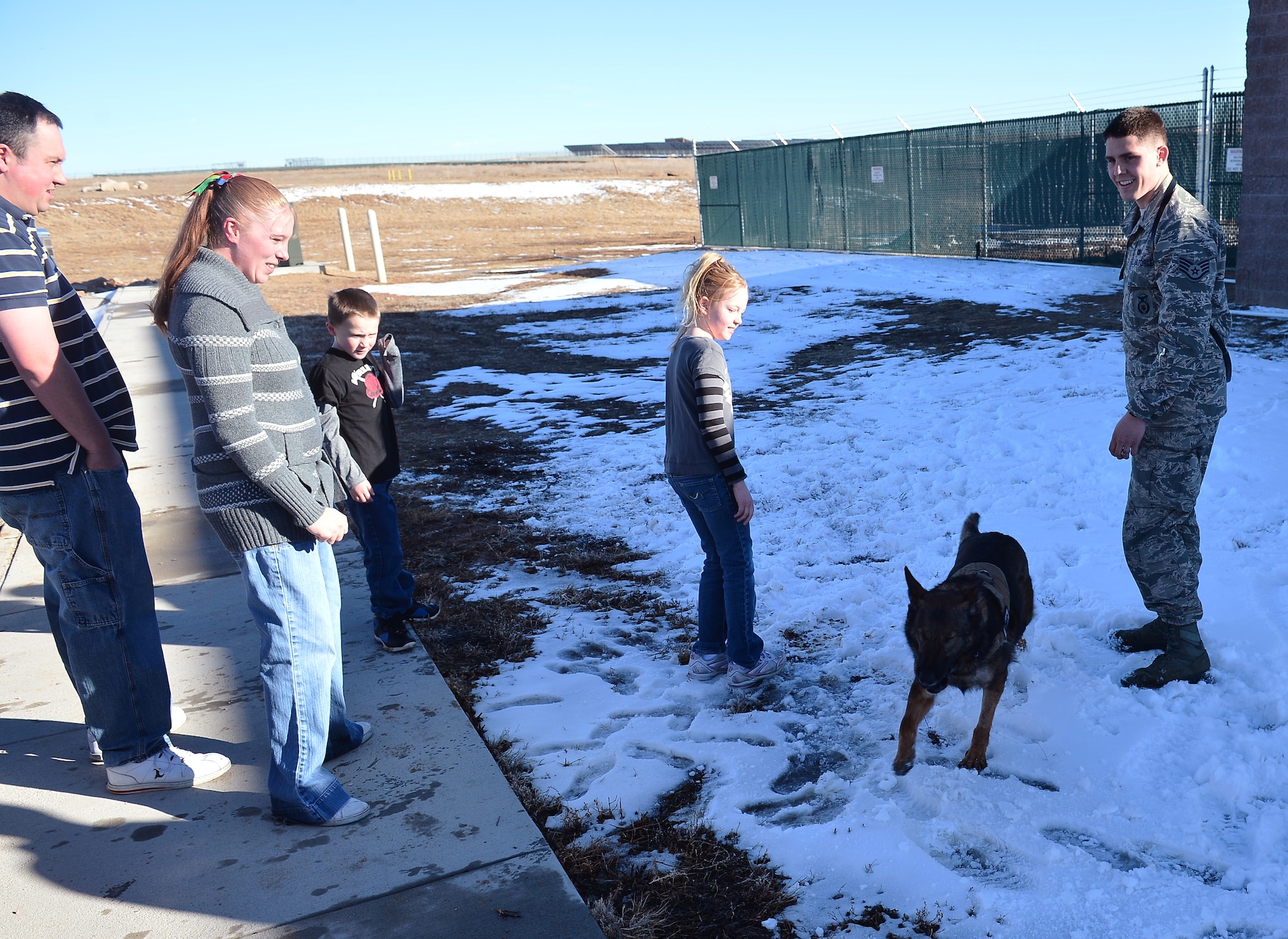 Staff Sgt. Jordan Gunterman, 460th Security Forces Squadron military working dog handler, right, and Nina, MWD, play with the Wulfers family Jan. 23, 2014, outside the 460th SFS kennels on Buckley Air Force Base, Colo. Gunterman was the first responder to a drunken driving car accident that affected the Wulfers family. (U.S. Air Force photo by Senior Airman Riley Johnson/Released)