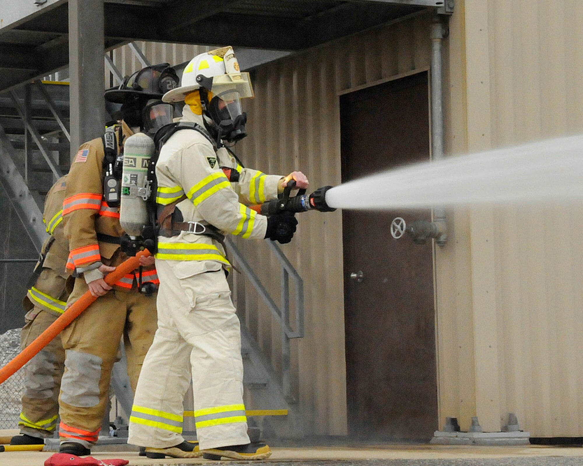 HANSCOM AIR FORCE BASE, Mass. – Col. Lester A. Weilacher, 66th Air Base Group commander, sprays a fire hose alongside Hanscom fire fighters at the fire training facility in the Civil Engineering complex April 11. The training provided Weilacher the experience of being a fire fighter. (U.S. Air Force photo by Linda LaBonte Britt)