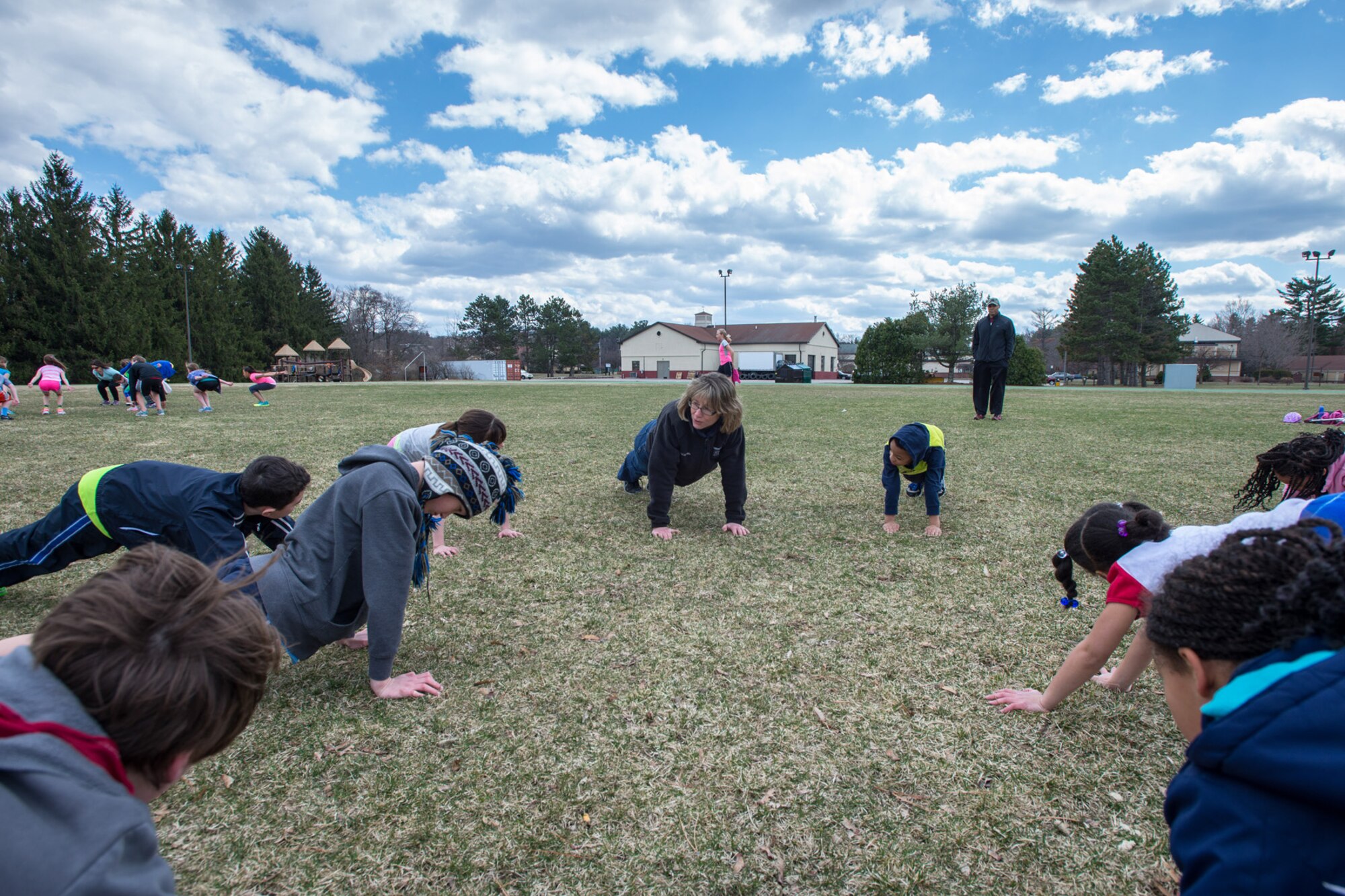 HANSCOM AIR FORCE BASE, Mass. – Barbara Cook, 66th Force Support Squadron Fitness Center recreation specialist, lead Hanscom youth ages nine to 14 in warm-up exercises at the base track April 9. Youth interested in participating the in the Hershey Youth Track Meet in June are invited to practice every Wednesday from 1:30 to 2:30 p.m. and Saturday from 9 to 10 a.m. at the track. Events include running, standing long jump and throwing. Participants do not have to come to every practice to enter the meet. For more information contact the Fitness Center at 781-225-6630. (U.S. Air Force photo by Rick Berry)