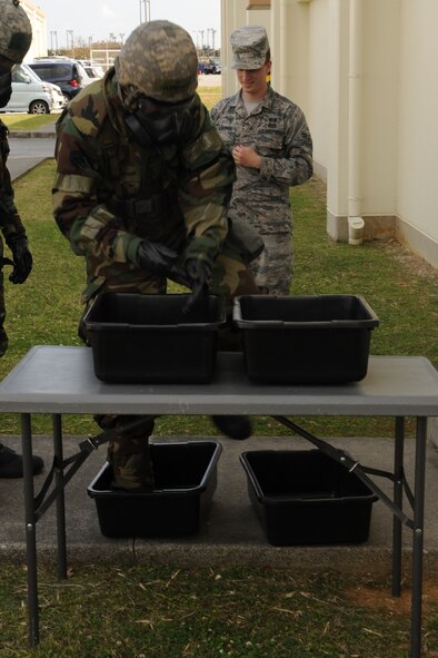 U.S. Air Force Airman 1st Class Brandon Schnathorst, 18th Equipment Maintenance Squadron metals technology journeyman, simulates decontaminating his Mission Oriented Protective Posture boots and gloves during Chemical, Biological, Radiological, Nuclear and Explosives training on Kadena Air Base, Japan, April 14, 2014. Decontaminating MOPP boots and gloves prevents hazardous materials, such as weaponized biological or chemical agents, from contaminating otherwise safe buildings. (U.S. Air Force photo by Airman 1st Class Zade C. Vadnais)