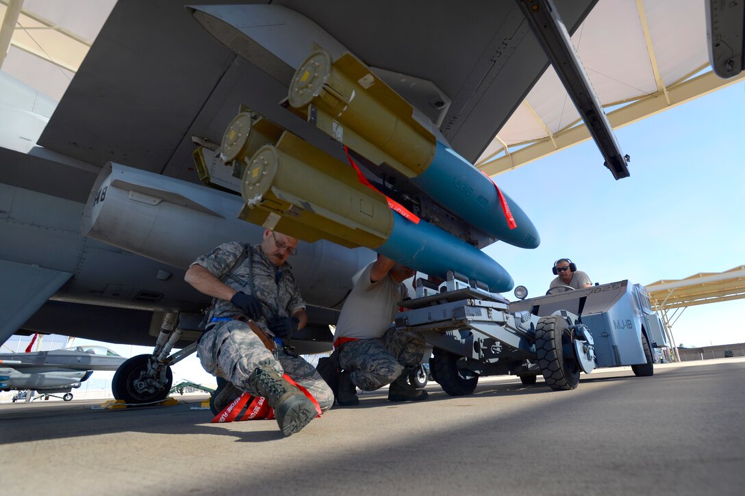 Air Force Tech. Sgts. Anthony Truesdale, left, Jacob Morales, center, and Donald Trevathan load an inert bomb onto an F-16 Fighting Falcon during Coronet Cactus on Davis-Monthan Air Force Base, Ariz., April 7, 2014. Truesdale, Morales and Trevathan are assigned to the 149th Aircraft Maintenance Squadron, Texas Air National Guard. 
