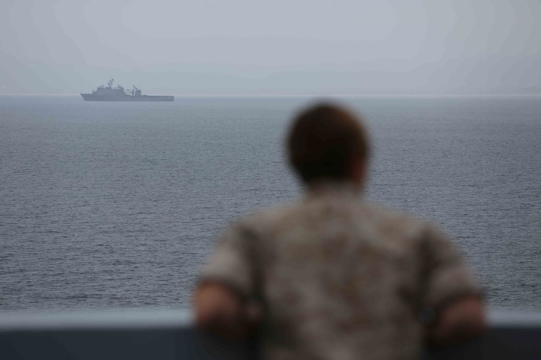 A Marine with the 11th Marine Expeditionary Unit looks out from the USS San Diego as the USS Comstock follows as part of a straits transit exercise during Amphibious Squadron Marine Expeditionary Unit Integration Training (PMINT) off the coast of San Diego, April 17, 2014. PMINT is a two-week predeployment training event focused on the combined capabilities of the MEU and Amphibious Ready Group (ARG), conducting amphibious operations, crisis response, and limited contingency operations. (U.S. Marine Corps photo by Cpl. Jonathan R. Waldman/RELEASED)