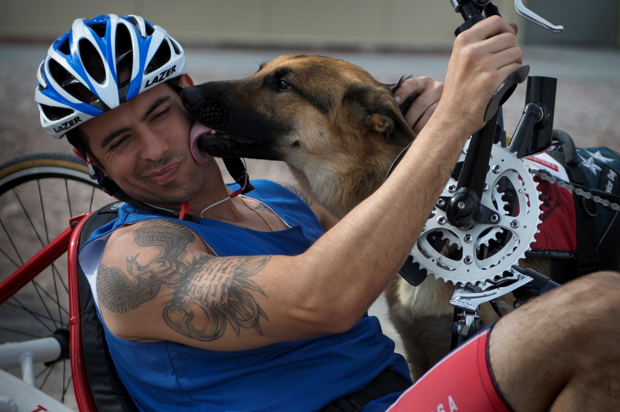 August O’Niell is kissed by his service dog, Kai, April 9, 2014, during the cycling portion of the Air Force Trials at Nellis Air Force Base, Nev. O’Neill, an Air Force wounded warrior, competed in the 6-mile men’s handcycle heat with four others. (U.S. Air Force photo/Senior Airman Jette Carr)