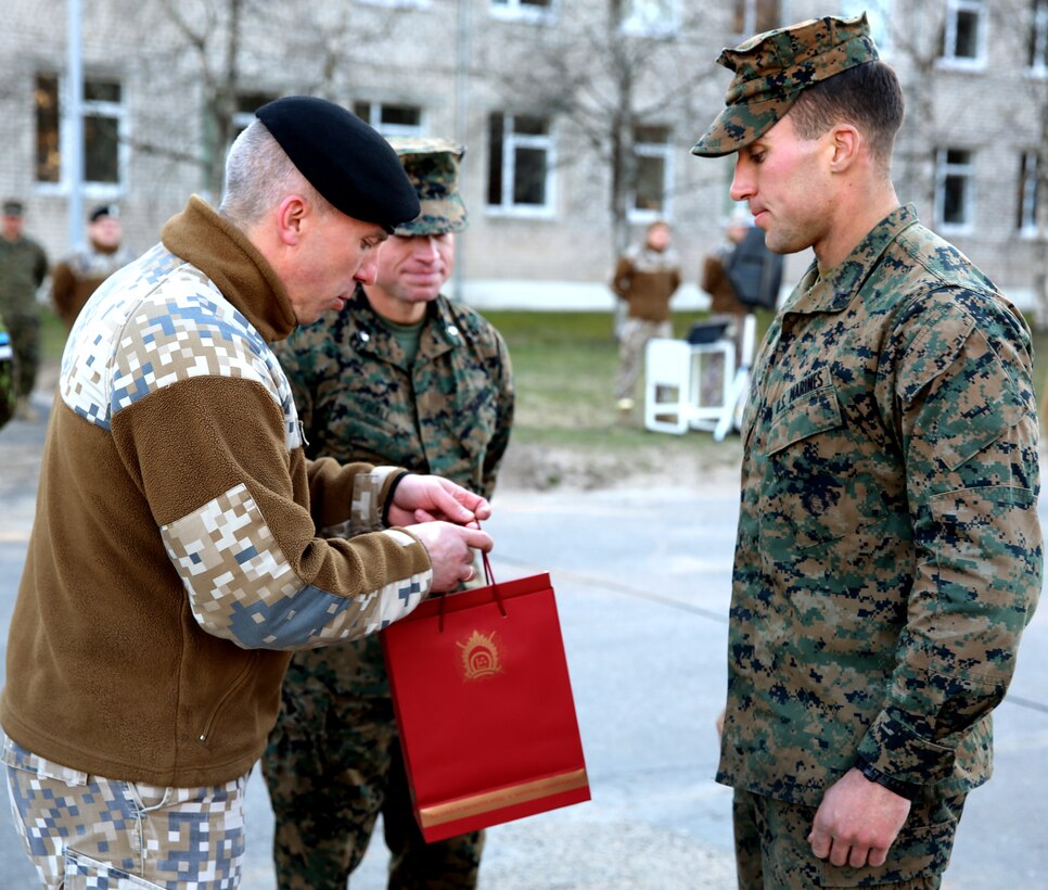 Latvian Lt. Col. Gunars Kaulins, the exercise director for exercise Summer Shield, presents a gift to U.S. Marine Lance Cpl. John Raisch, awarding him as the best Marine of the exercise during Summer Shield’s closing ceremony aboard Camp Adazi, Latvia, April 16, 2014. This is the 11th iteration of the Summer Shield exercise, a joint staff planning and live-fire maneuver event designed to enhance the NATO force’s capacity and capability to integrate combined arms and maneuver at the battalion and brigade level. It also increases partner capacity, promotes regional stability, and enhances Latvian, Lithuanian, Estonian, and U.S. interoperability as NATO allies. (Official Marine Corps photo by Lance Cpl. Scott W. Whiting, BSRF PAO/ Released)