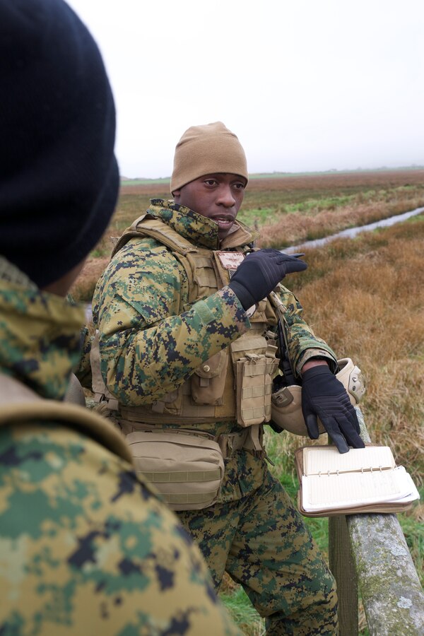 Corporal Tariek Leith, a radio chief with 4th Air Naval Gunfire Liaison Company, Force Headquarters Group, Marine Forces Reserve instructs a junior Marine on proper radio dialogue between ground units and notional flight platforms overhead in preparation for an assault exercise April 8, during exercise Joint Warrior 2014. During Joint Warrior, Marines worked alongside their British counter parts in the United Kingdom to strengthen interoperability ties. 