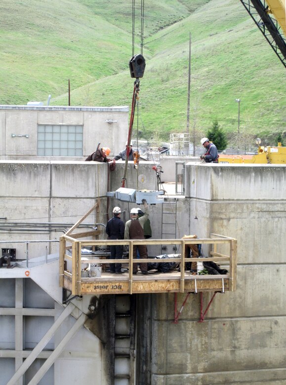 Contractor workers at Little Goose Dam install the new gudgeon arm assembly on the top of the navigation lock’s downstream south gate leaf.