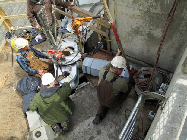Contractor workers at Little Goose Dam install the new gudgeon arm assembly on the top of the navigation lock’s downstream south gate leaf.