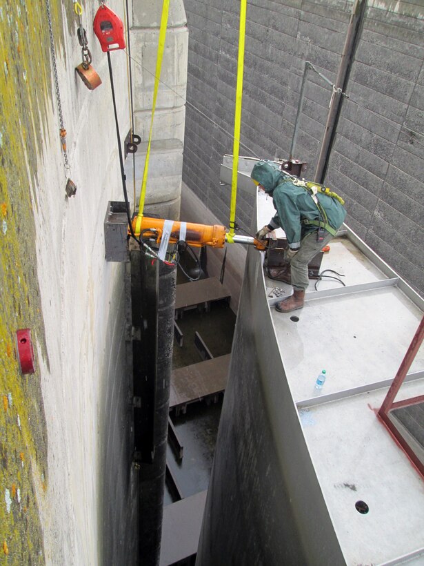 Workers place hydraulic jacks between the downstream north gate leaf and the navigation lock wall to use while adjusting the diagonal tensioning of the gate. Correct tensioning of each gate will help prevent the massive structures from twisting.