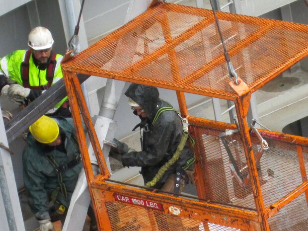 Workers on the gate and in a crane-suspended man basket adjust the diagonal-tensioning nuts on the downstream north navigation lock gate leaf.  Correct tensioning of each gate will help prevent the massive structures from twisting.