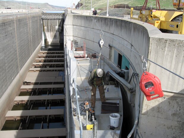 Contractor workers prepare Little Goose Dam’s downstream south navigation lock gate leaf for removing the old, cracked gudgeon assembly. This requires installing retaining brackets on the top, and jacking and shoring equipment under the bottom of the gate to keep it stabile against the navigation lock wall during work.